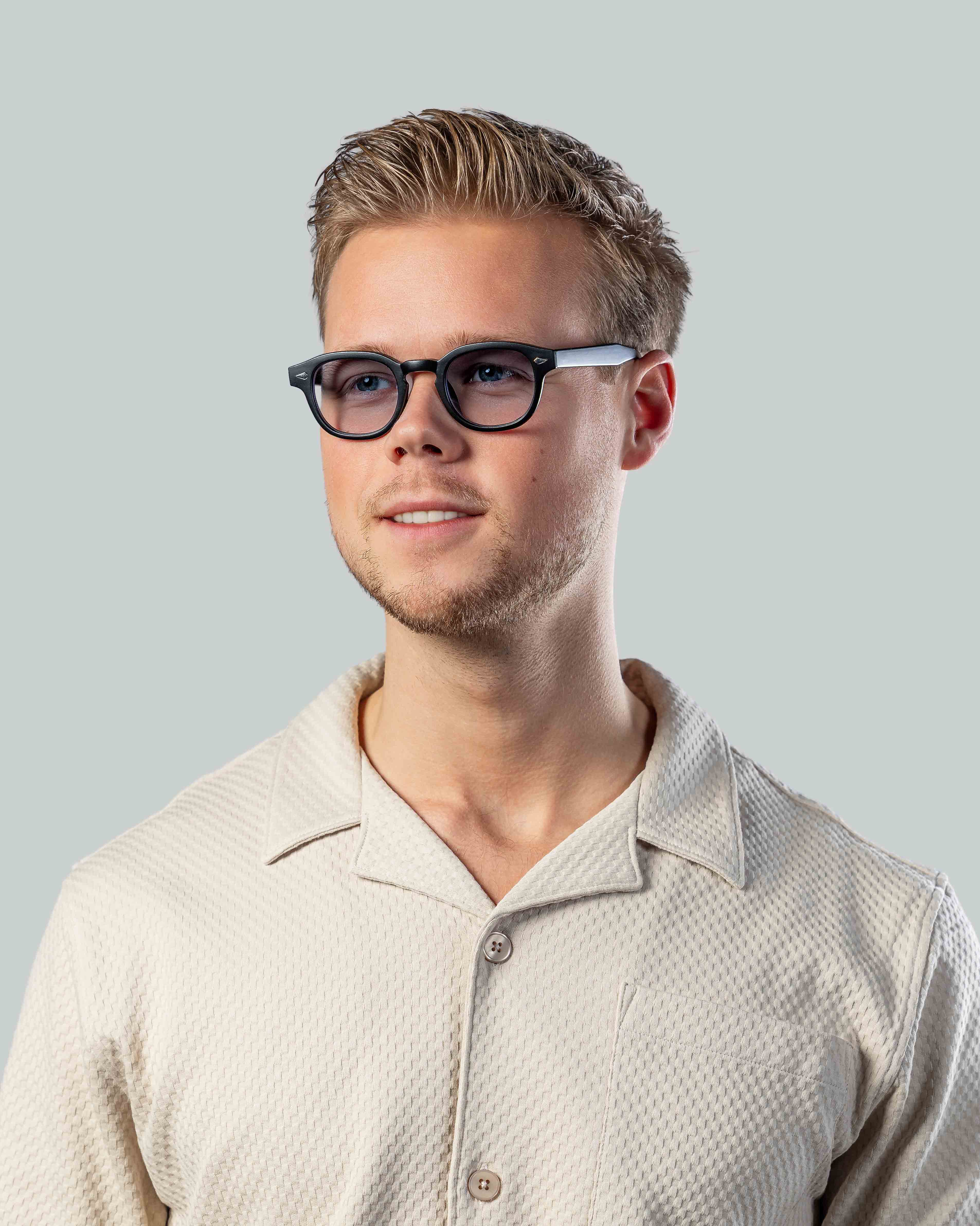 Stijlvolle zonnebril met zwarte montuur en zilveren details, gedragen door man in lichte shirt