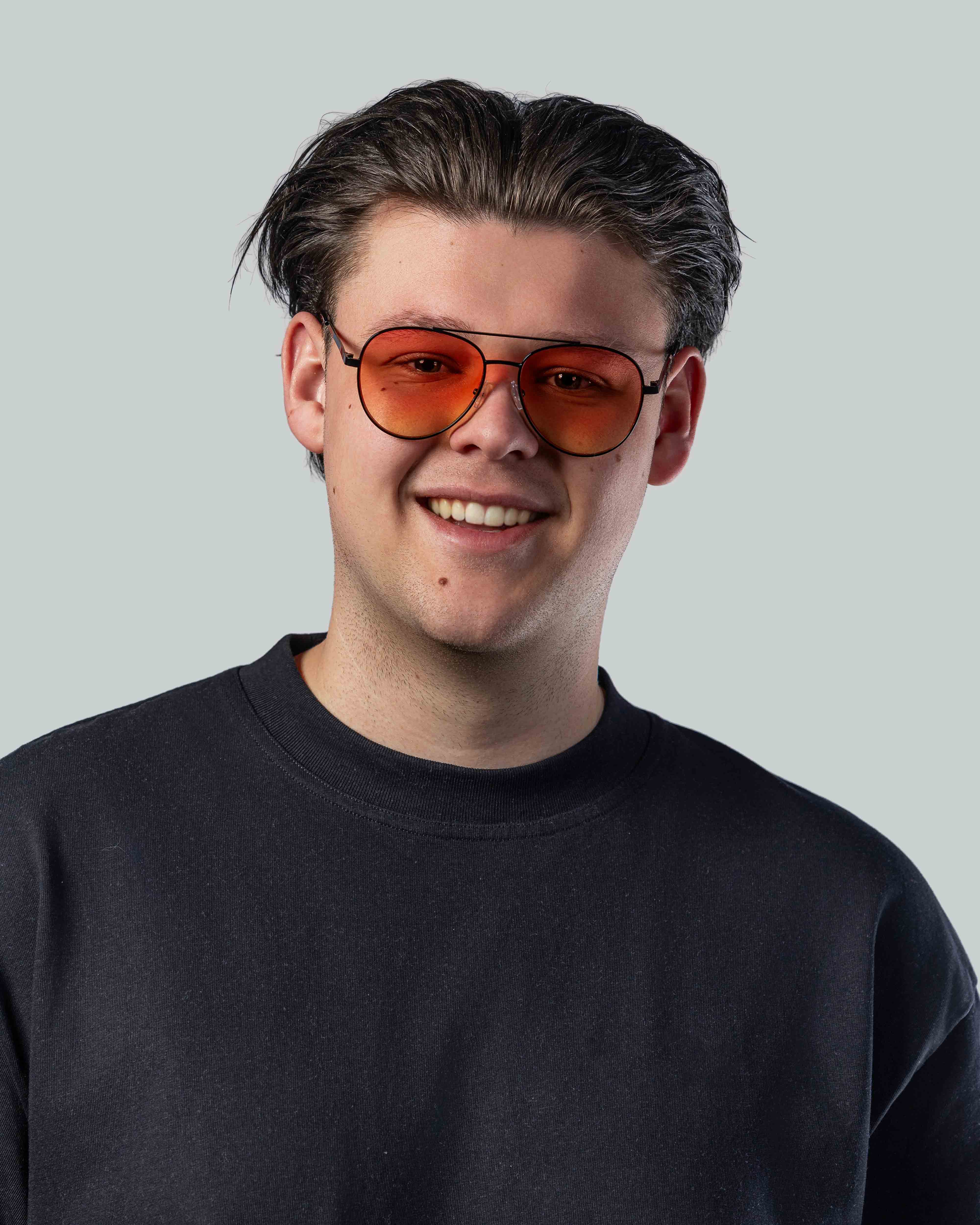 Man met stijlvolle zonnebril met oranje glazen en zwarte montuur, perfect voor een trendy look.