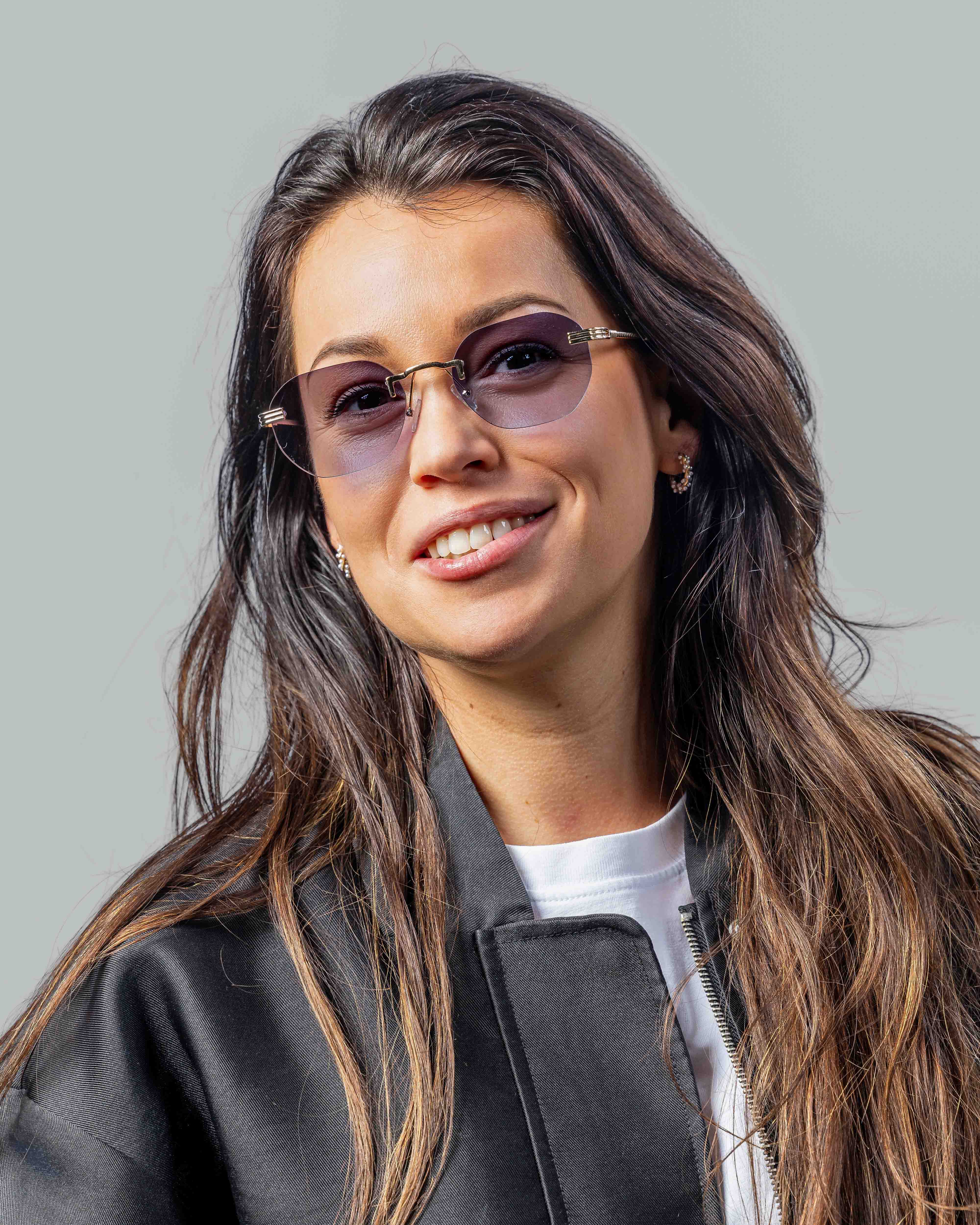 Vrouw met stijlvolle zonnebril, paarse glazen en gouden montuur, perfect voor een modieuze look.