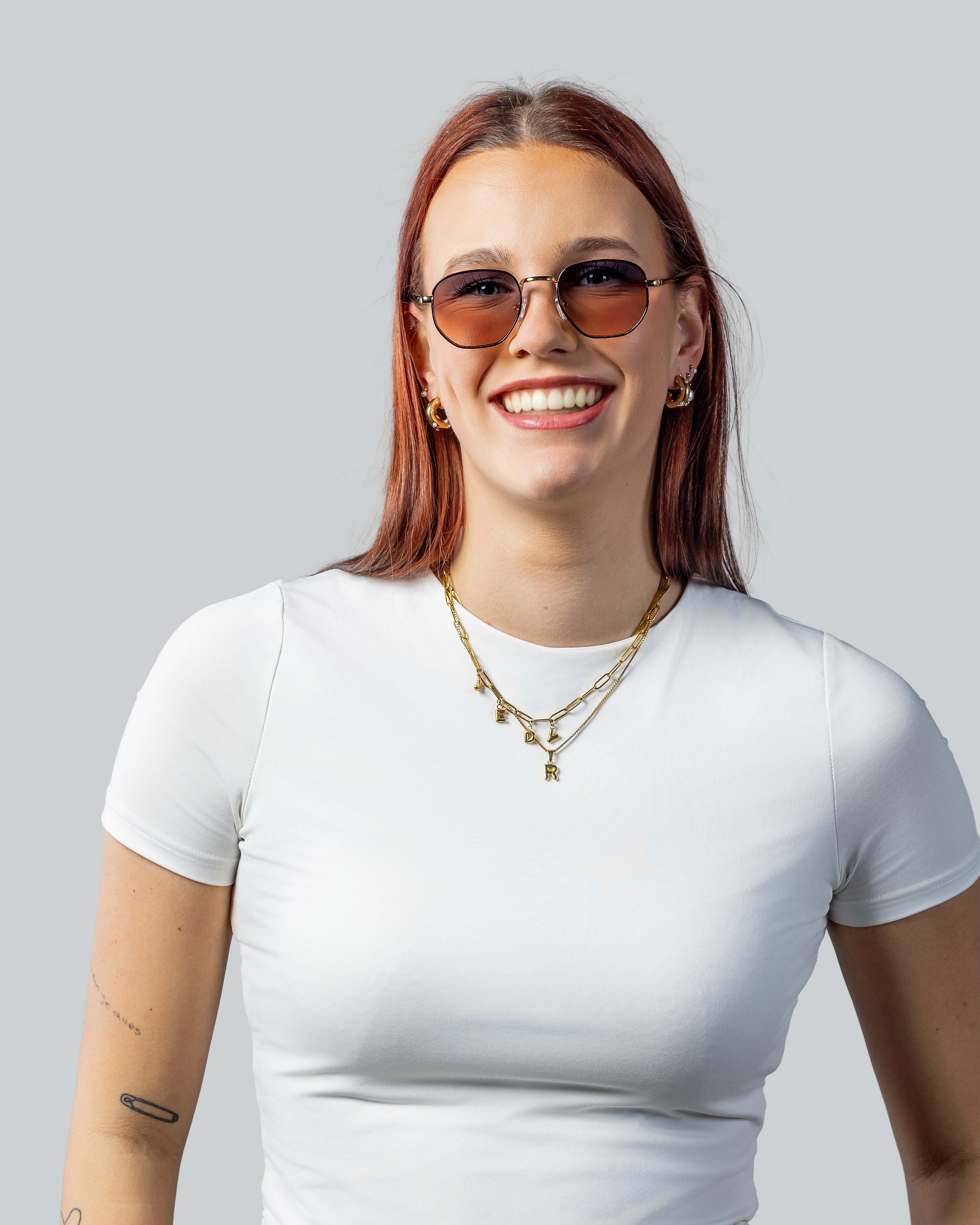 Vrouw met stijlvolle zonnebril en gouden sieraden, perfect voor een trendy look