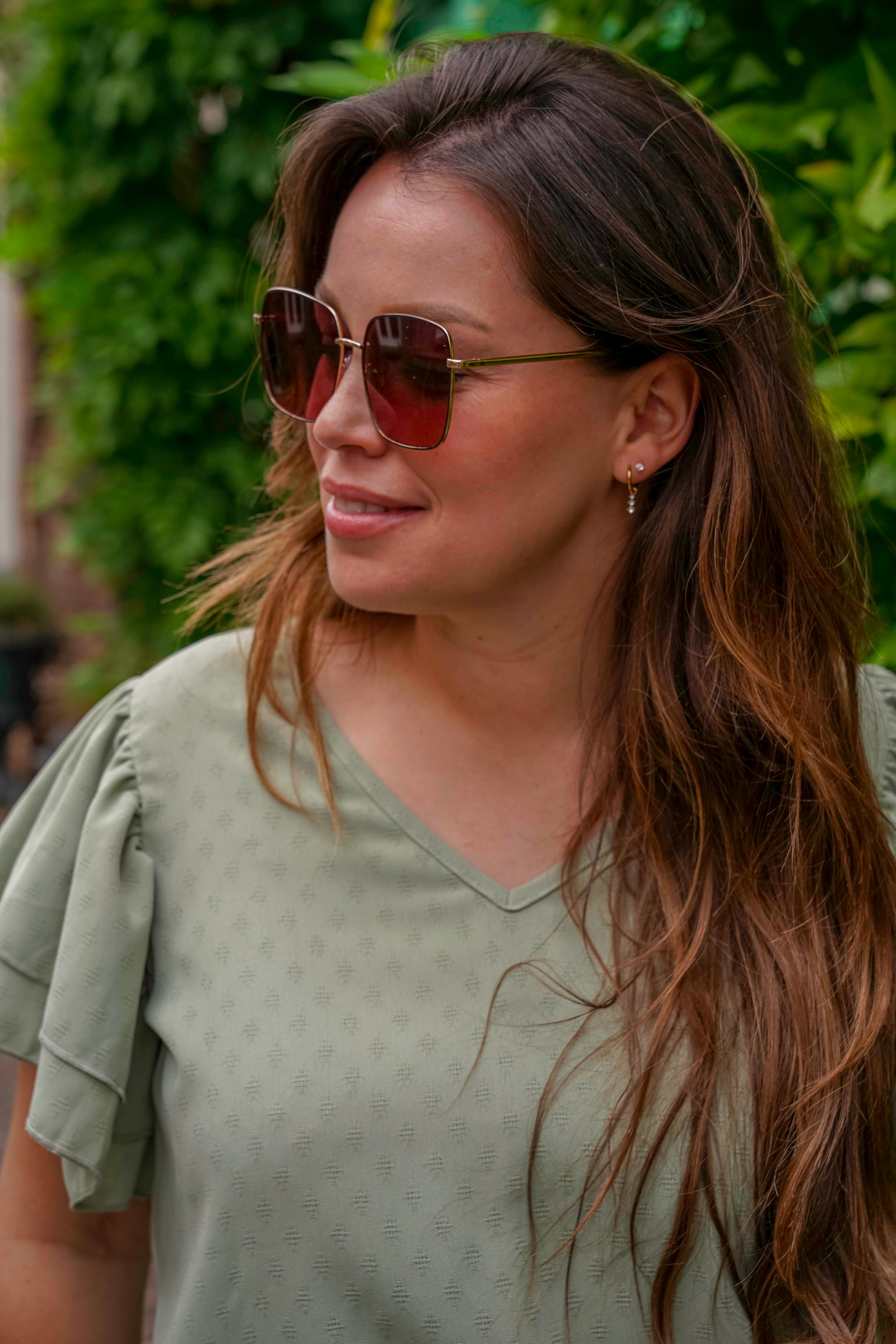 Vrouw met stijlvolle zonnebril en groen shirt, perfect voor zonnige dagen