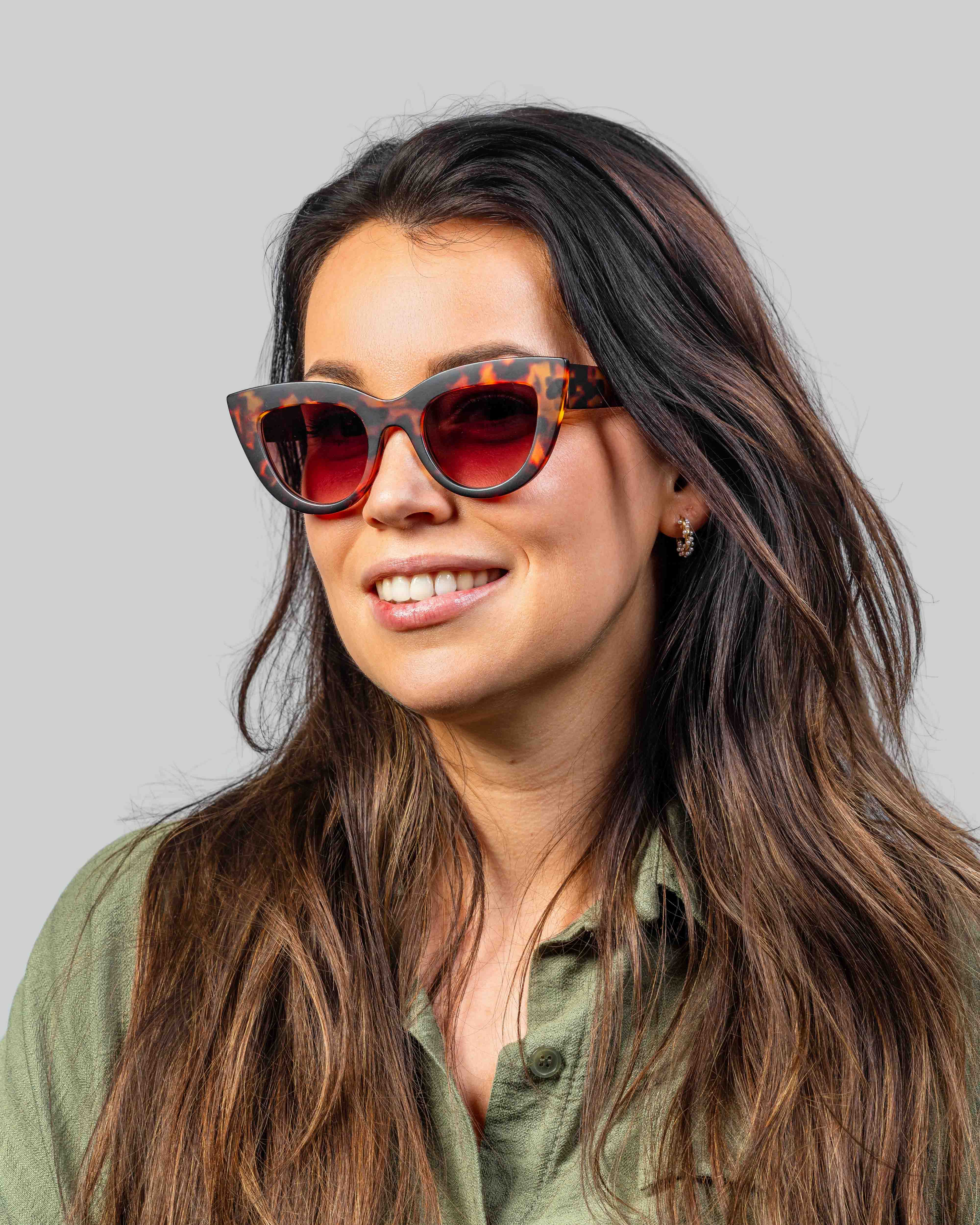 Vrouw met stijlvolle tortoise zonnebril en rode glazen, perfect voor zomerse dagen.