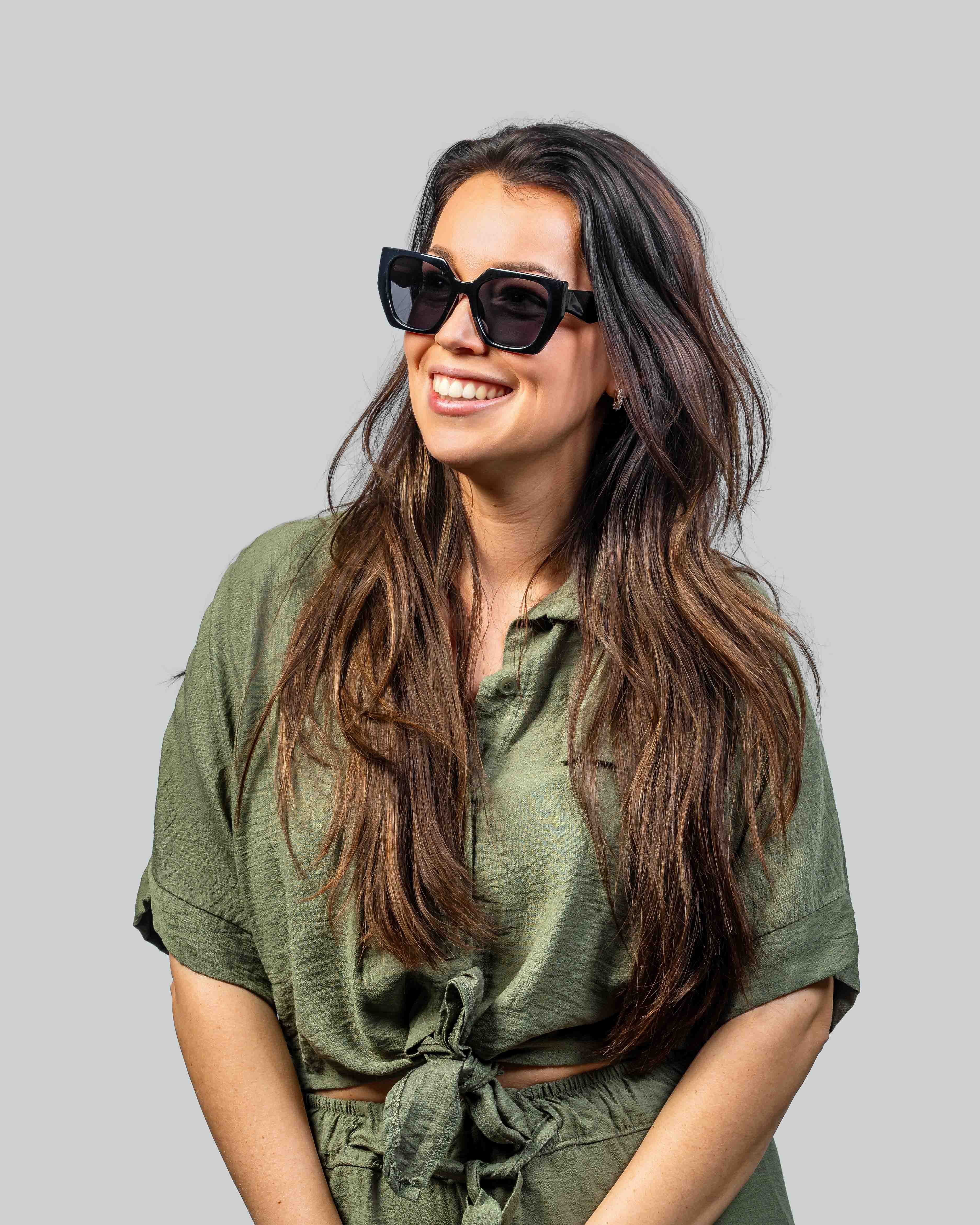 Vrouw met stijlvolle zwarte zonnebril en groene outfit, perfect voor zomerse dagen