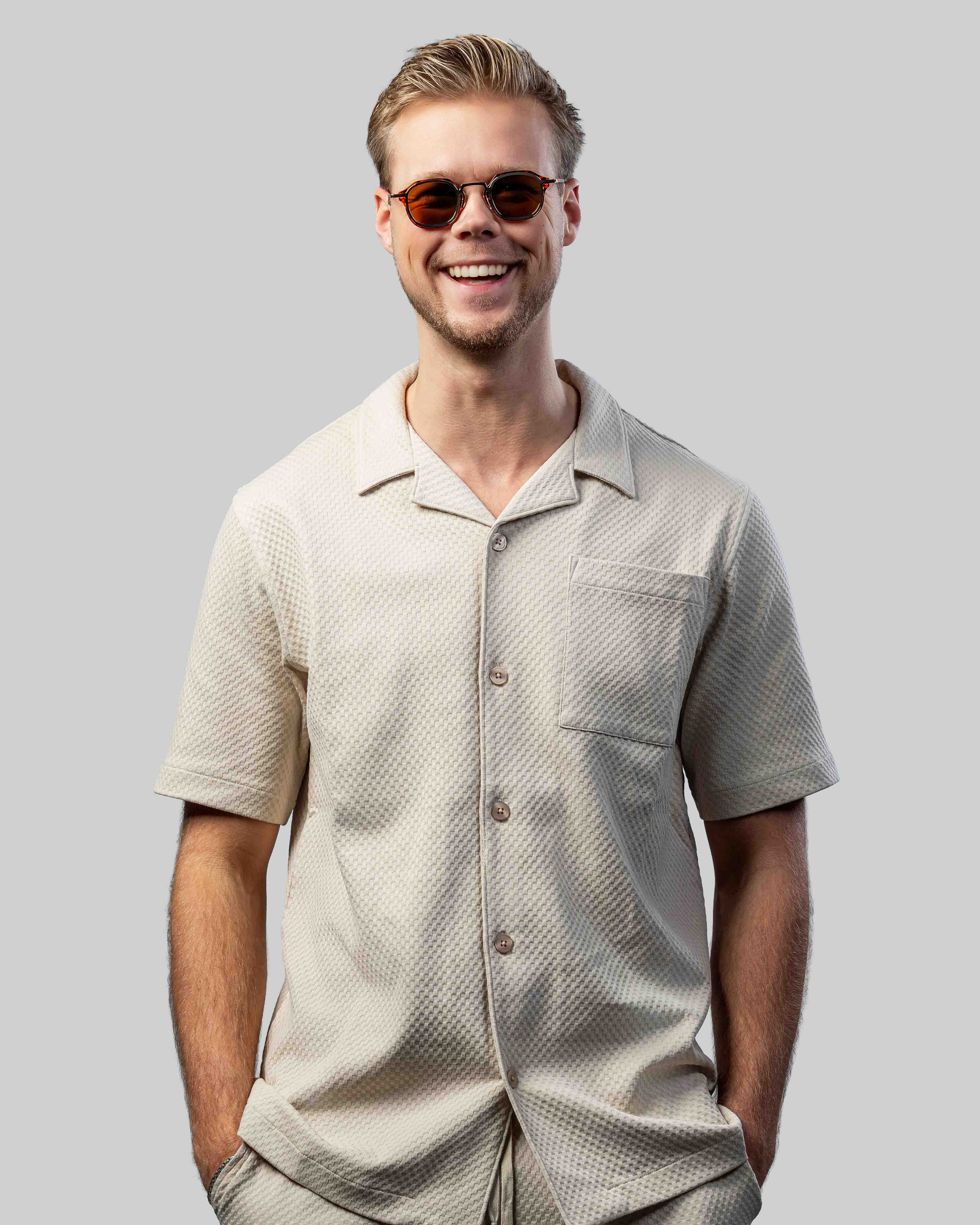 Man met stijlvolle zonnebril en lichte overhemd, perfect voor zomerse dagen.