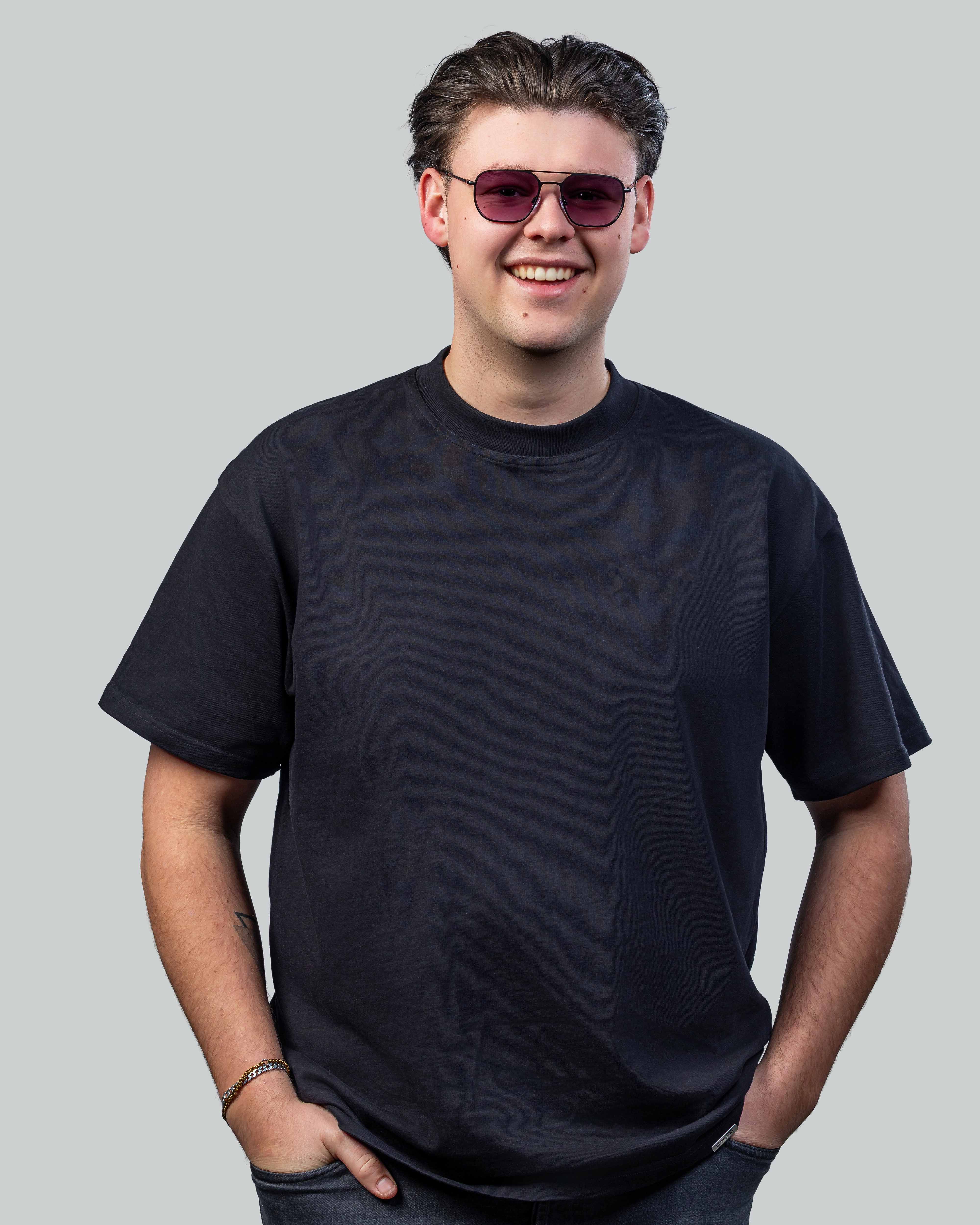 Stijlvolle zonnebril met paarse glazen en dunne montuur, gedragen door jonge man in zwarte t-shirt