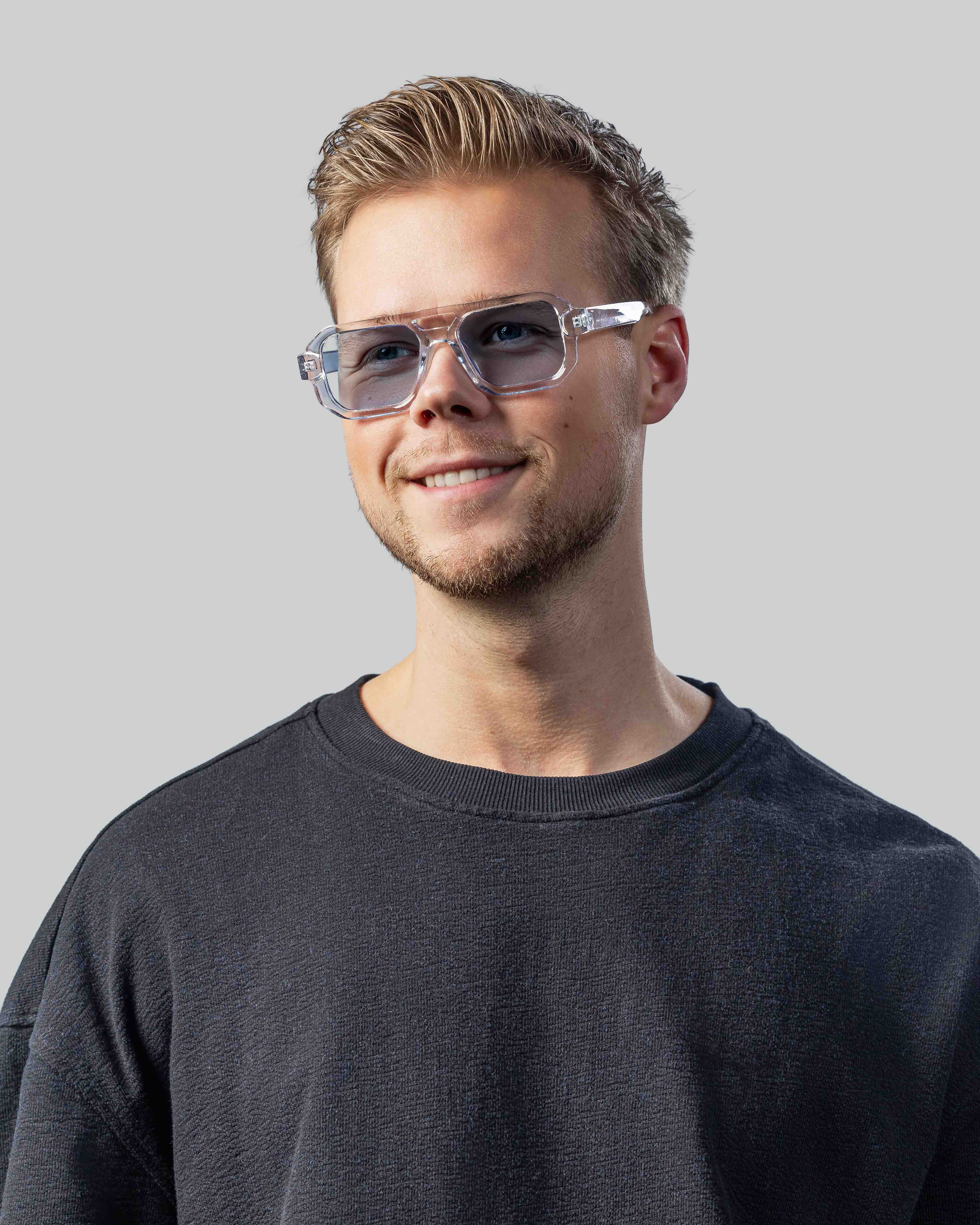 Man met stijlvolle, transparante zonnebril en grijze sweater, perfect voor een moderne look.
