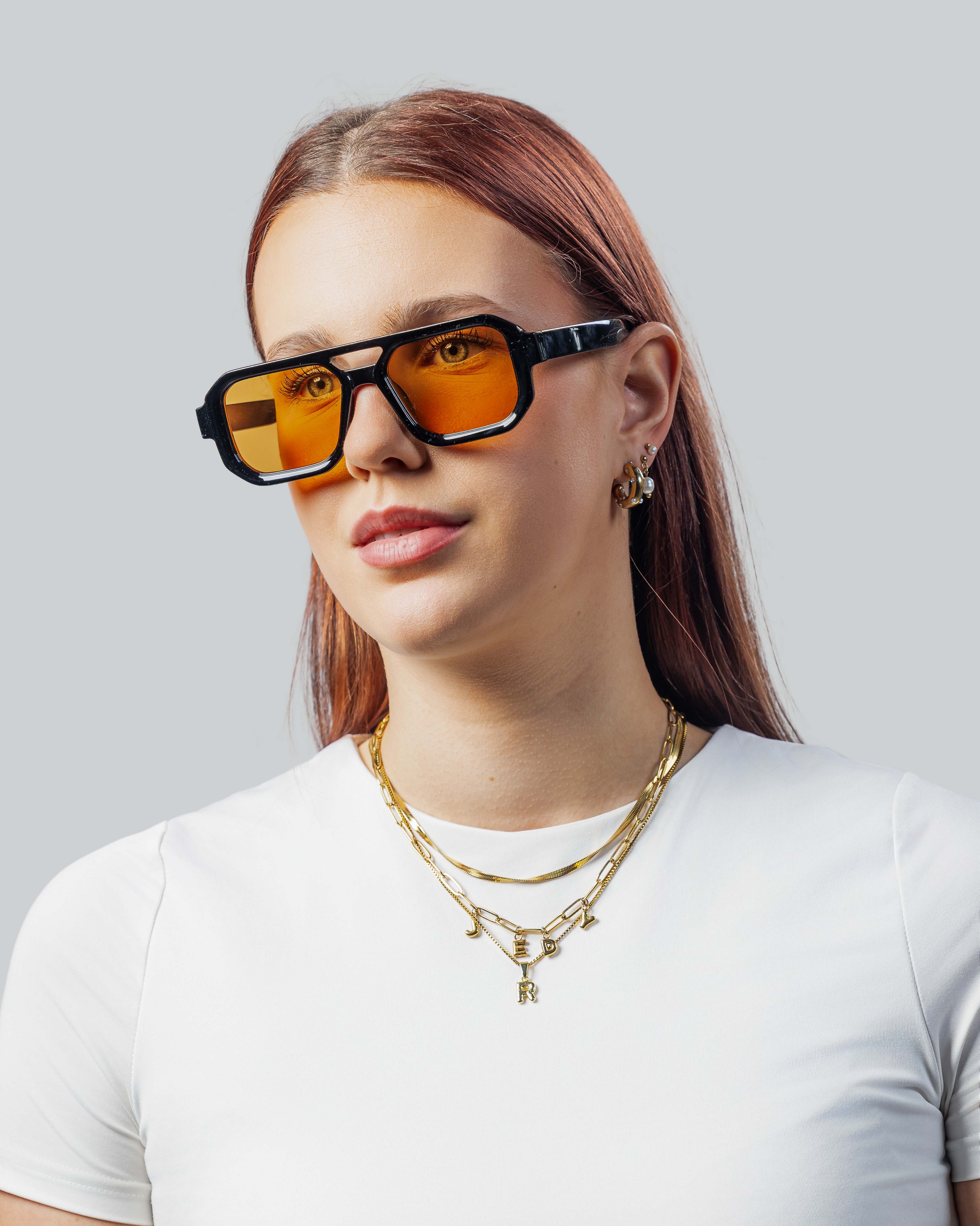 Vrouw met stijlvolle zonnebril met oranje glazen en zwarte montuur, perfect voor een trendy look.