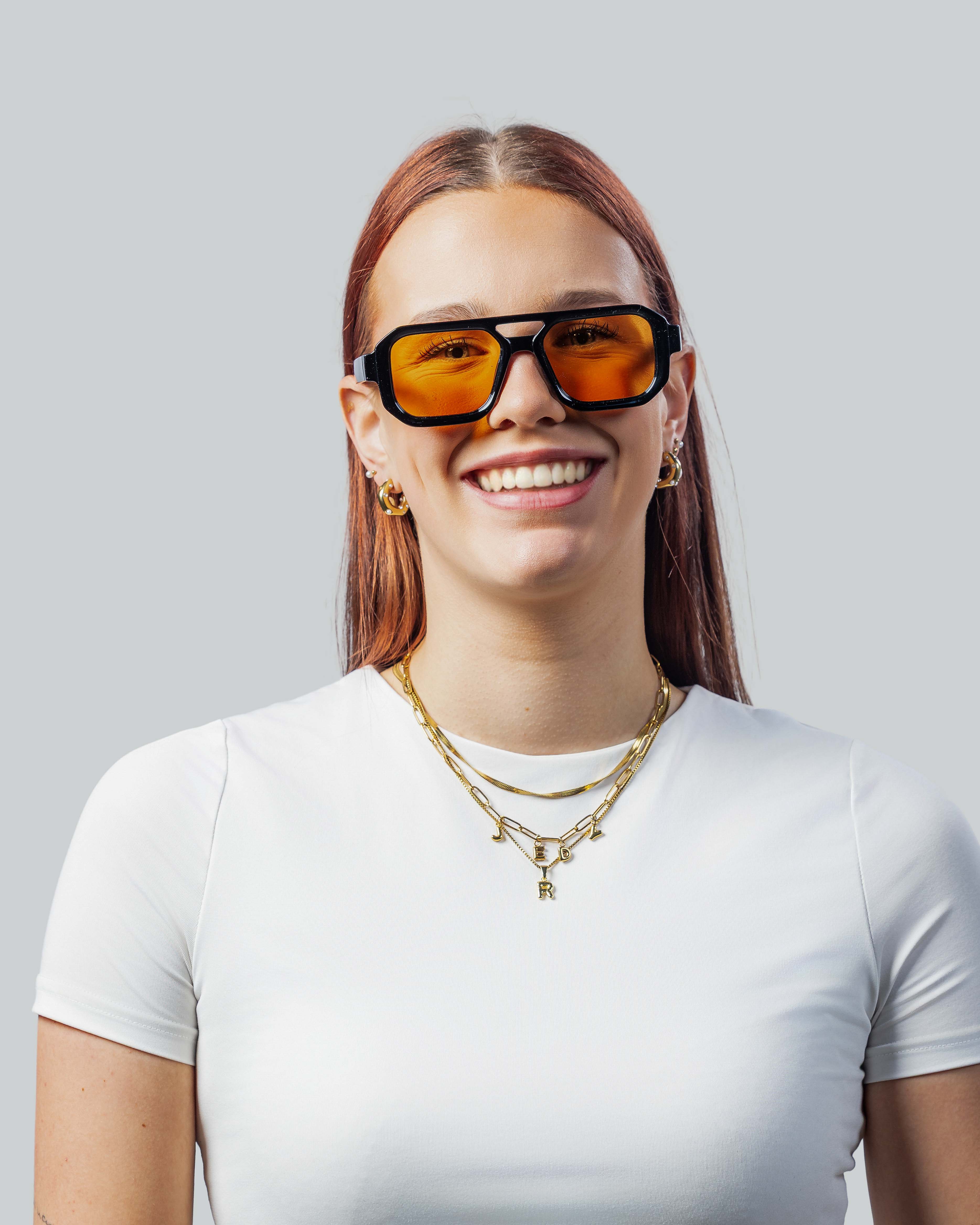 Vrouw met stijlvolle zonnebril met oranje glazen en zwarte montuur, perfect voor een trendy look.