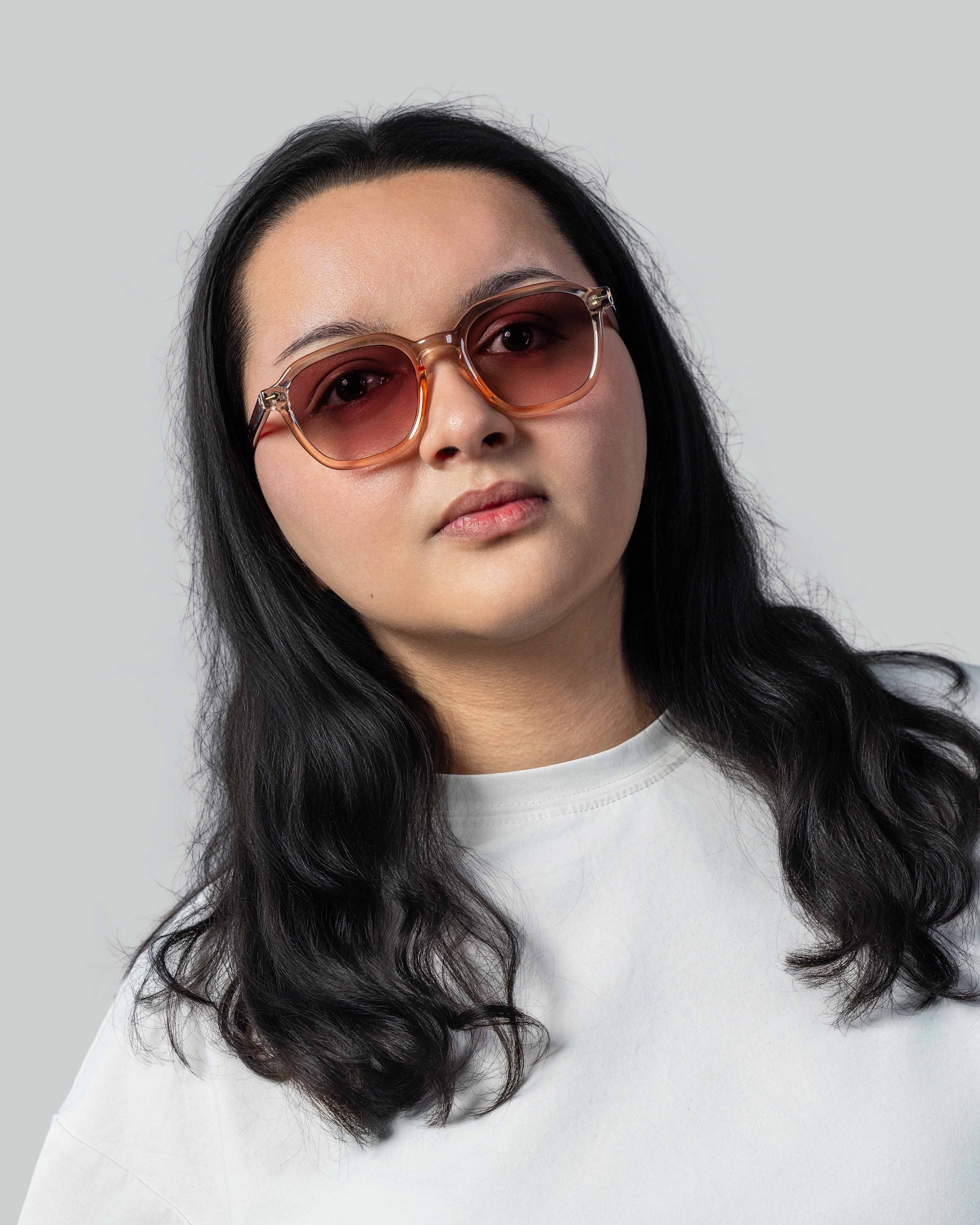 Vrouw met stijlvolle zonnebril, bruine glazen en transparante montuur, perfect voor een trendy look.