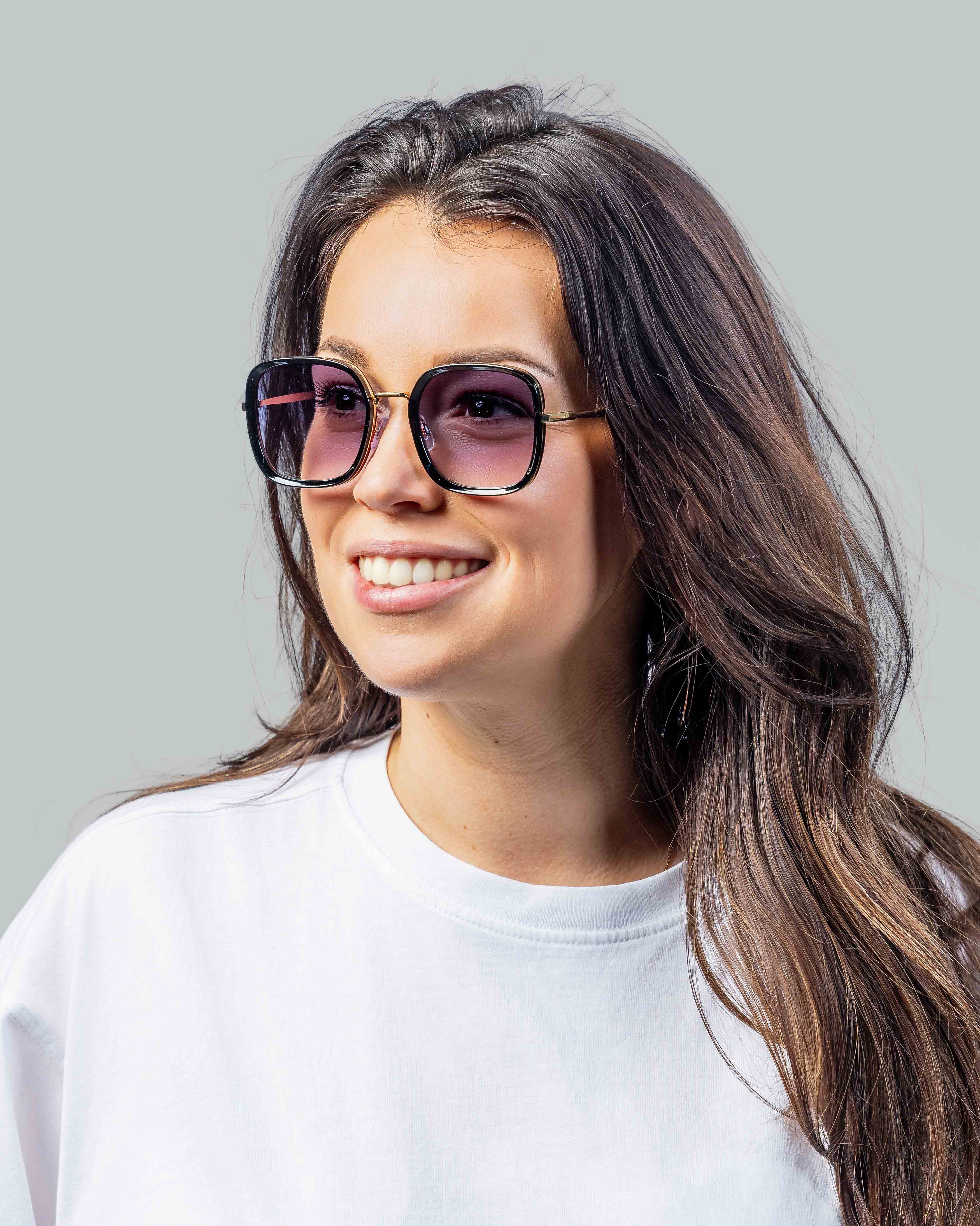 Vrouw met stijlvolle zonnebril, roze getinte glazen en goudkleurige montuur, perfect voor zomerse dagen.