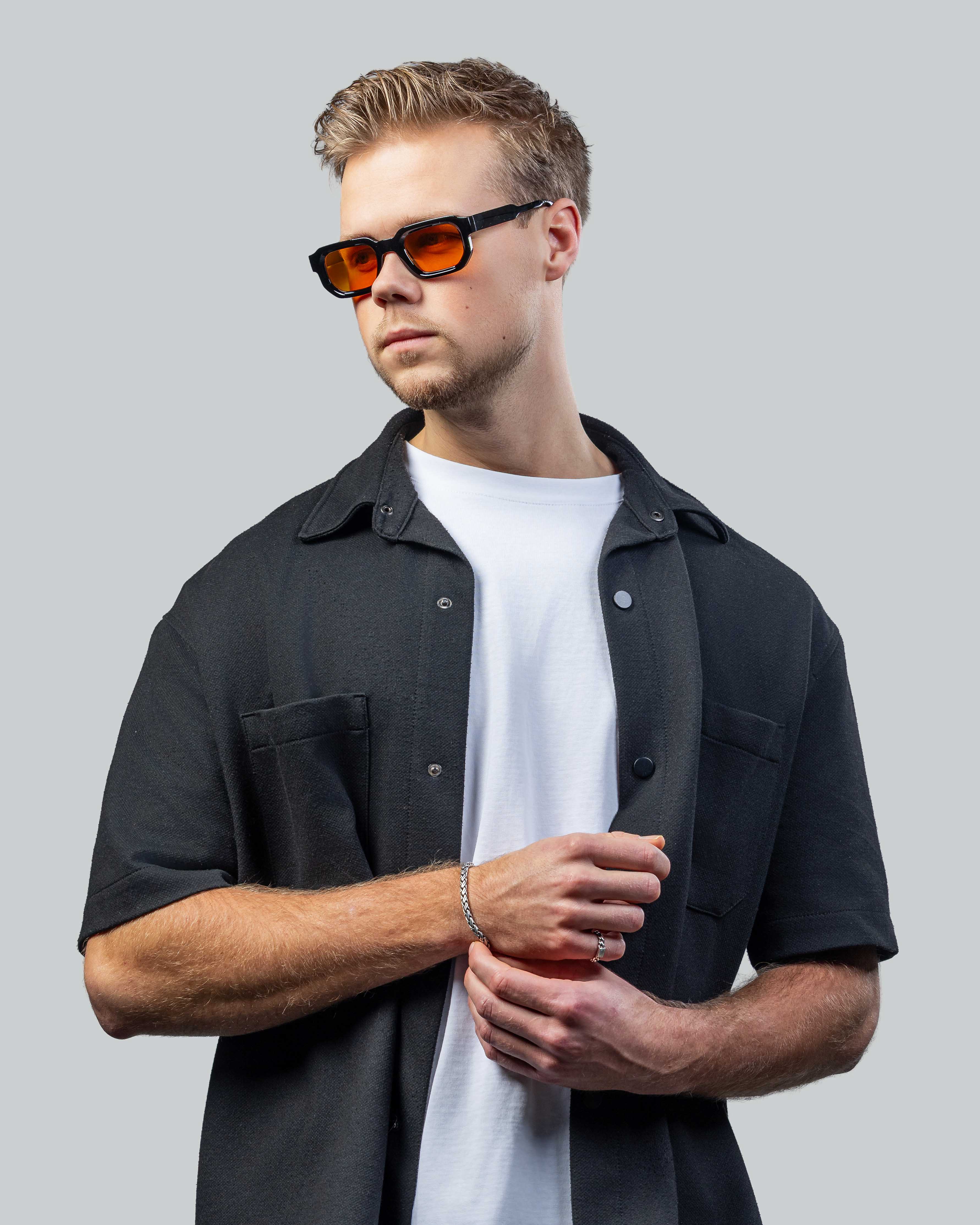 Man met stijlvolle zonnebril met oranje glazen en zwarte montuur, perfect voor een moderne look.