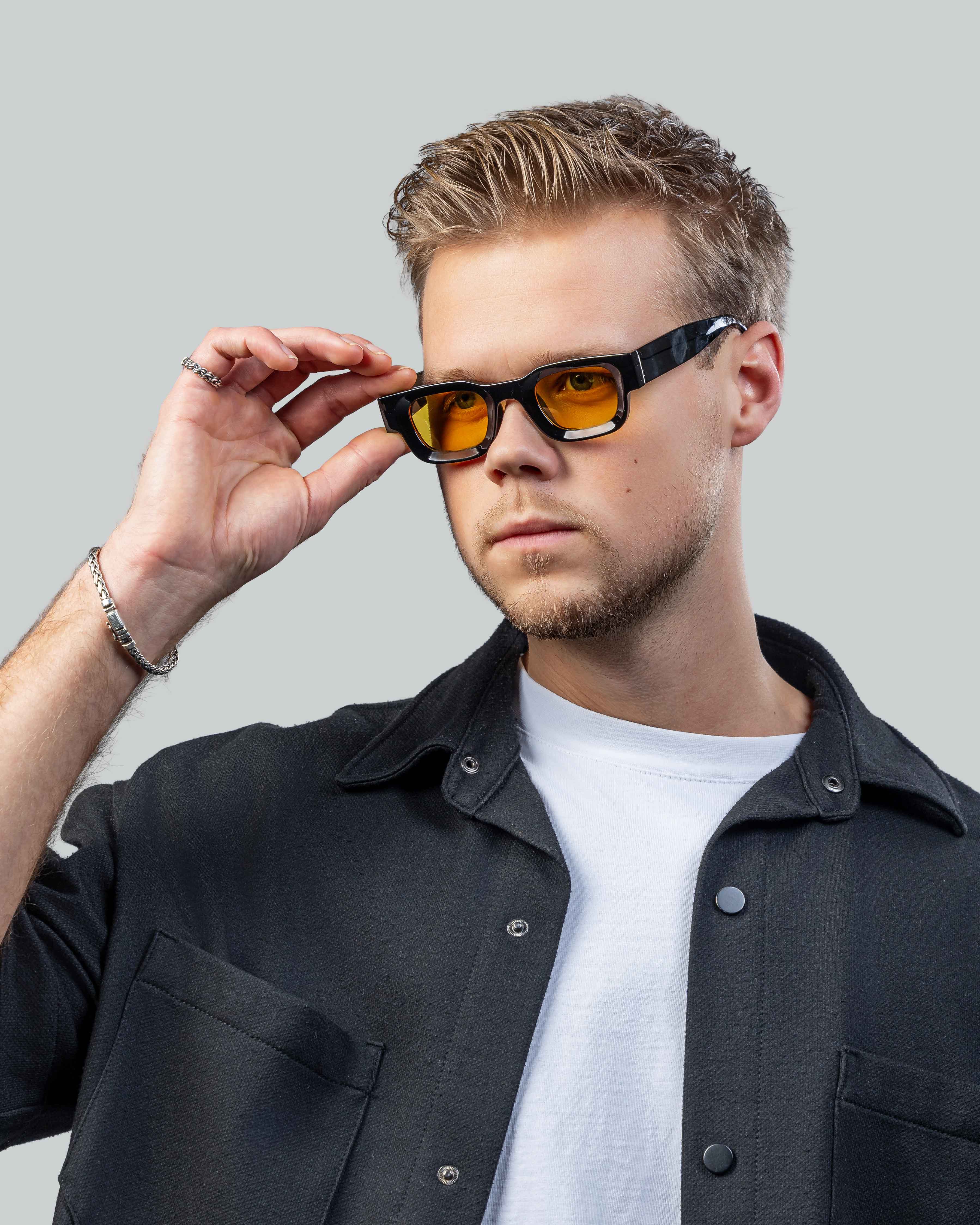 Man met stijlvolle zonnebril met oranje glazen en zwarte montuur, perfect voor een trendy look.