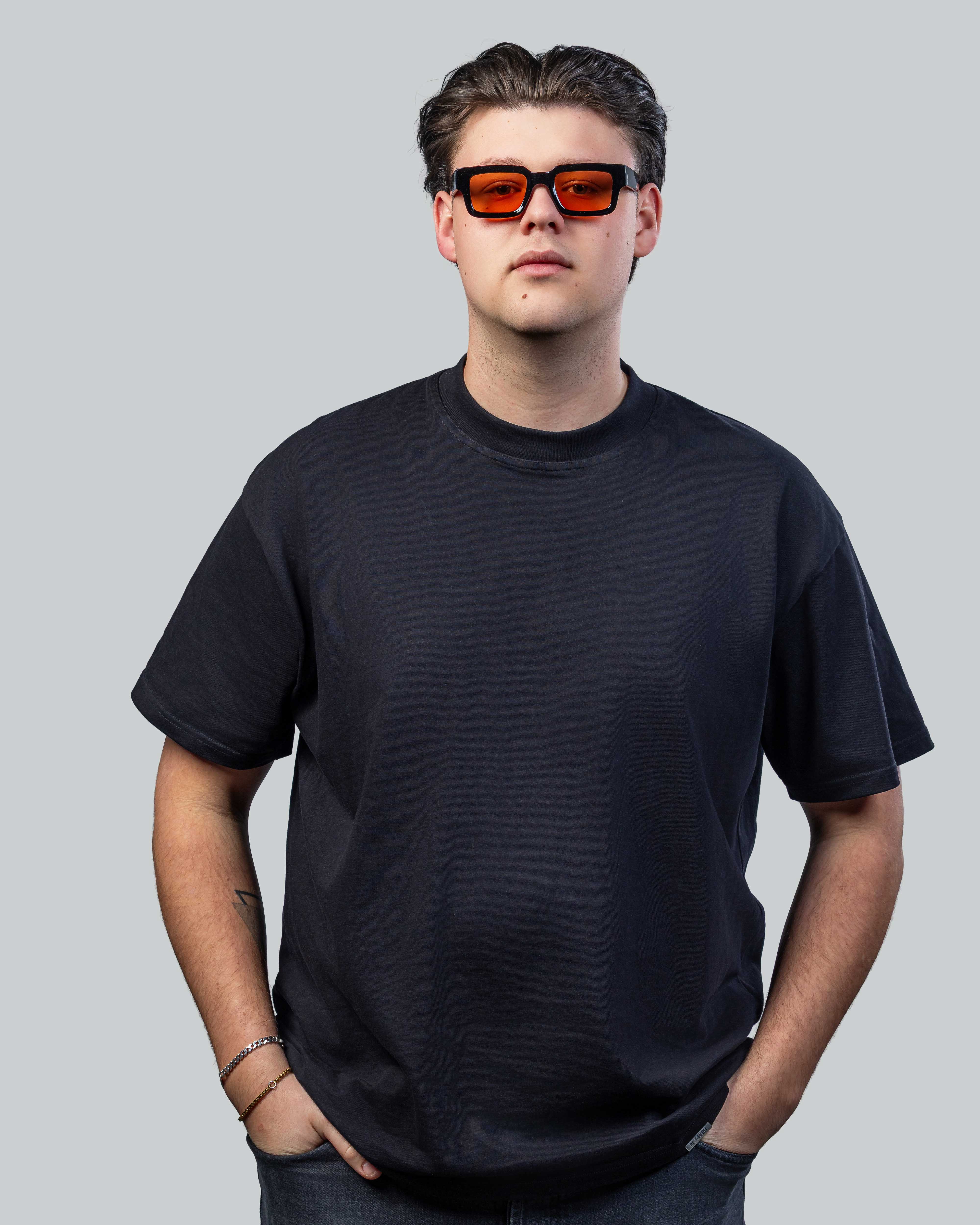 Man met stijlvolle zonnebril met oranje glazen en zwarte montuur, perfect voor een trendy look.