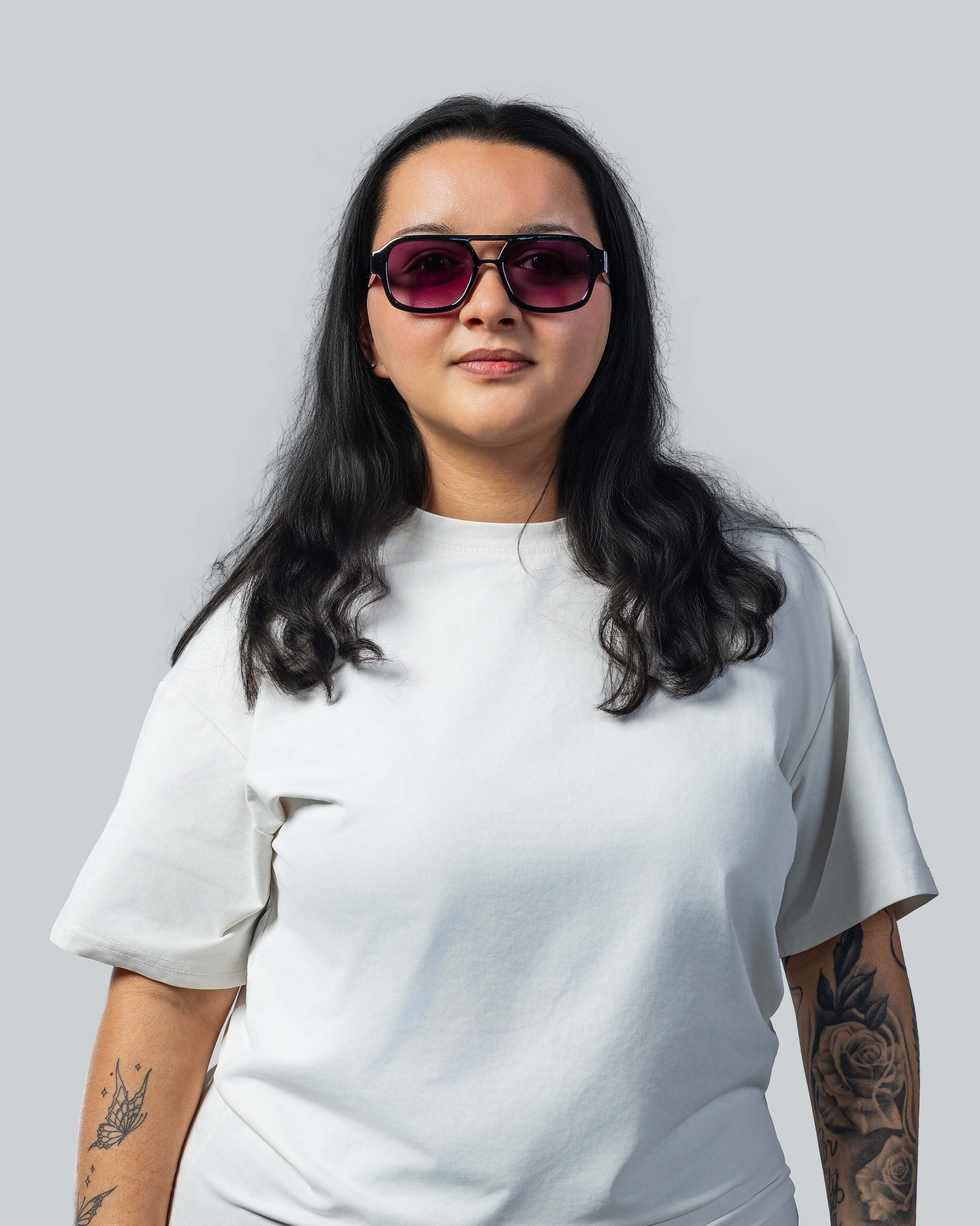 Vrouw met stijlvolle zonnebril, paarse glazen en zwart montuur, perfect voor een trendy look.