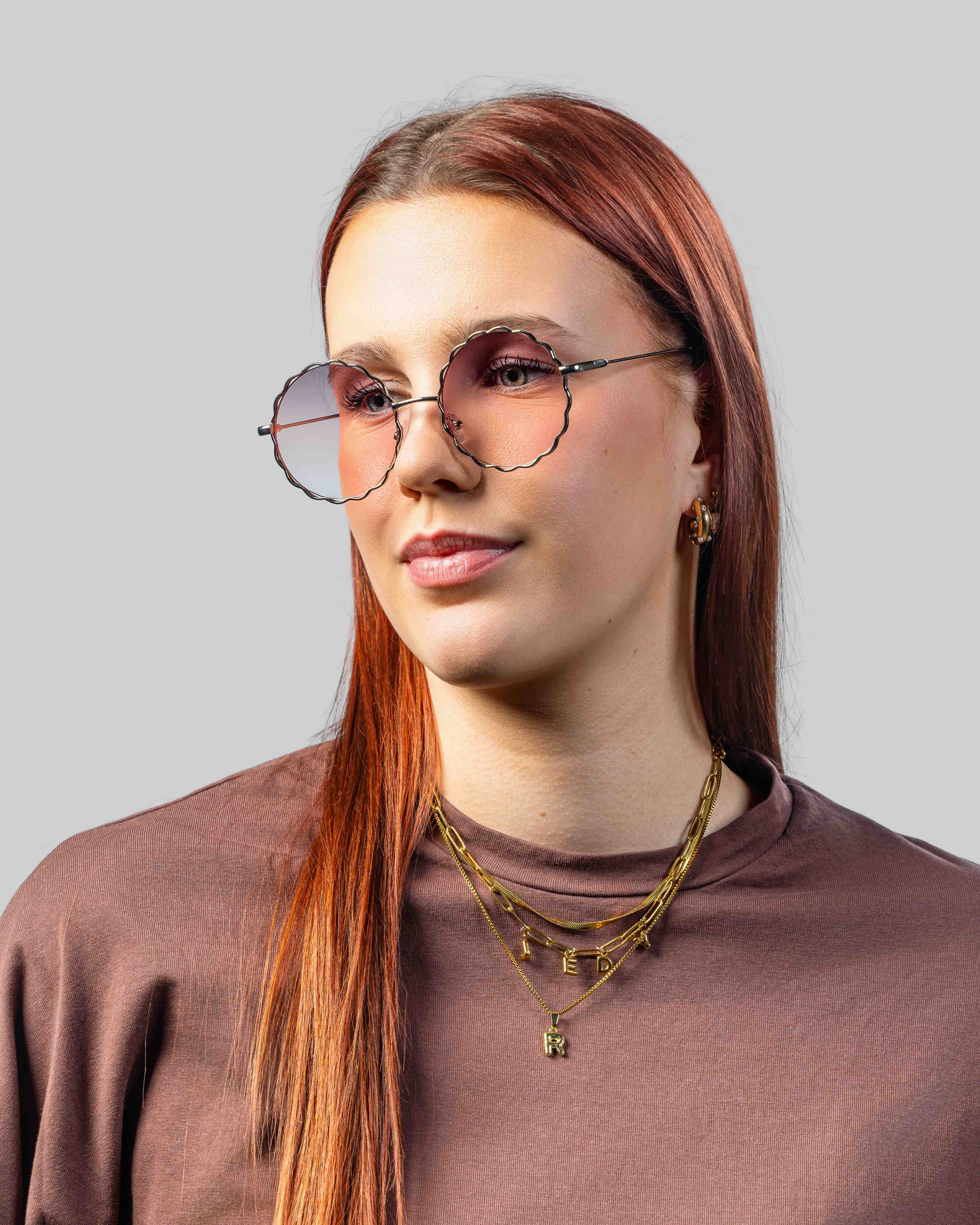 Vrouw met stijlvolle zonnebril met golvende rand en roze glazen, perfect voor een modieuze look.