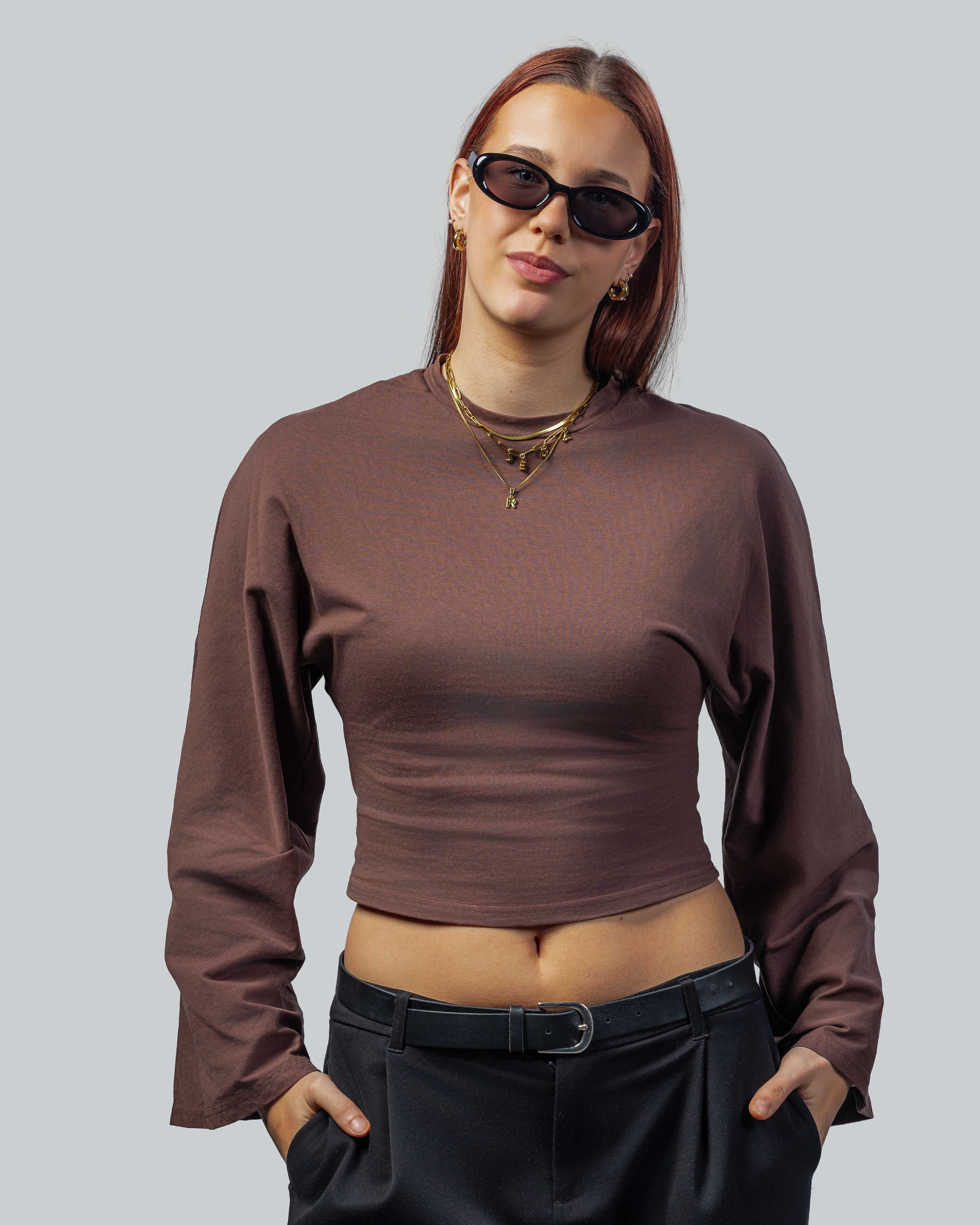 Vrouw met stijlvolle zonnebril, bruine cropped trui en zwarte broek, perfect voor een trendy look.