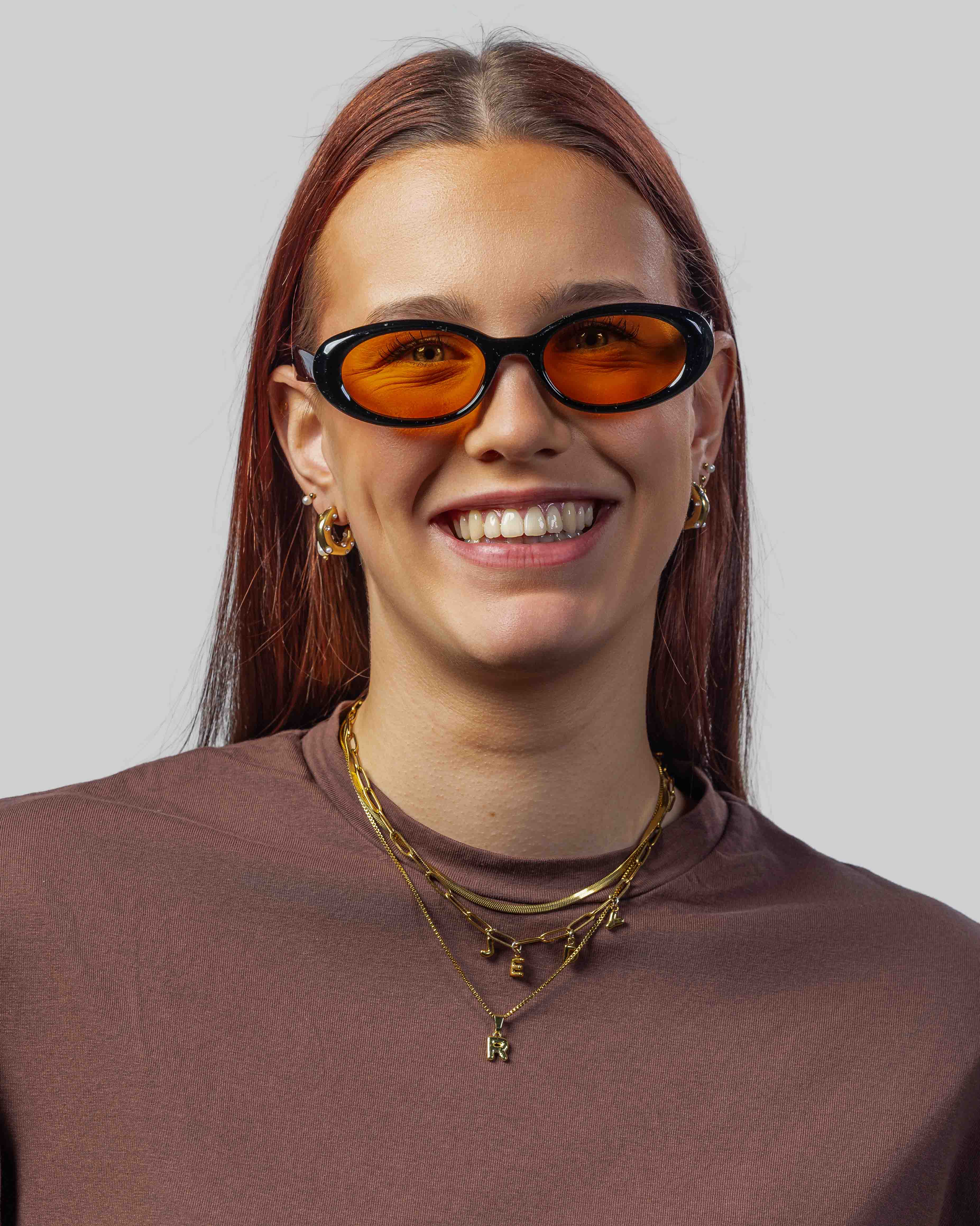Vrouw met stijlvolle zonnebril met oranje glazen en zwarte montuur, perfect voor een trendy look.