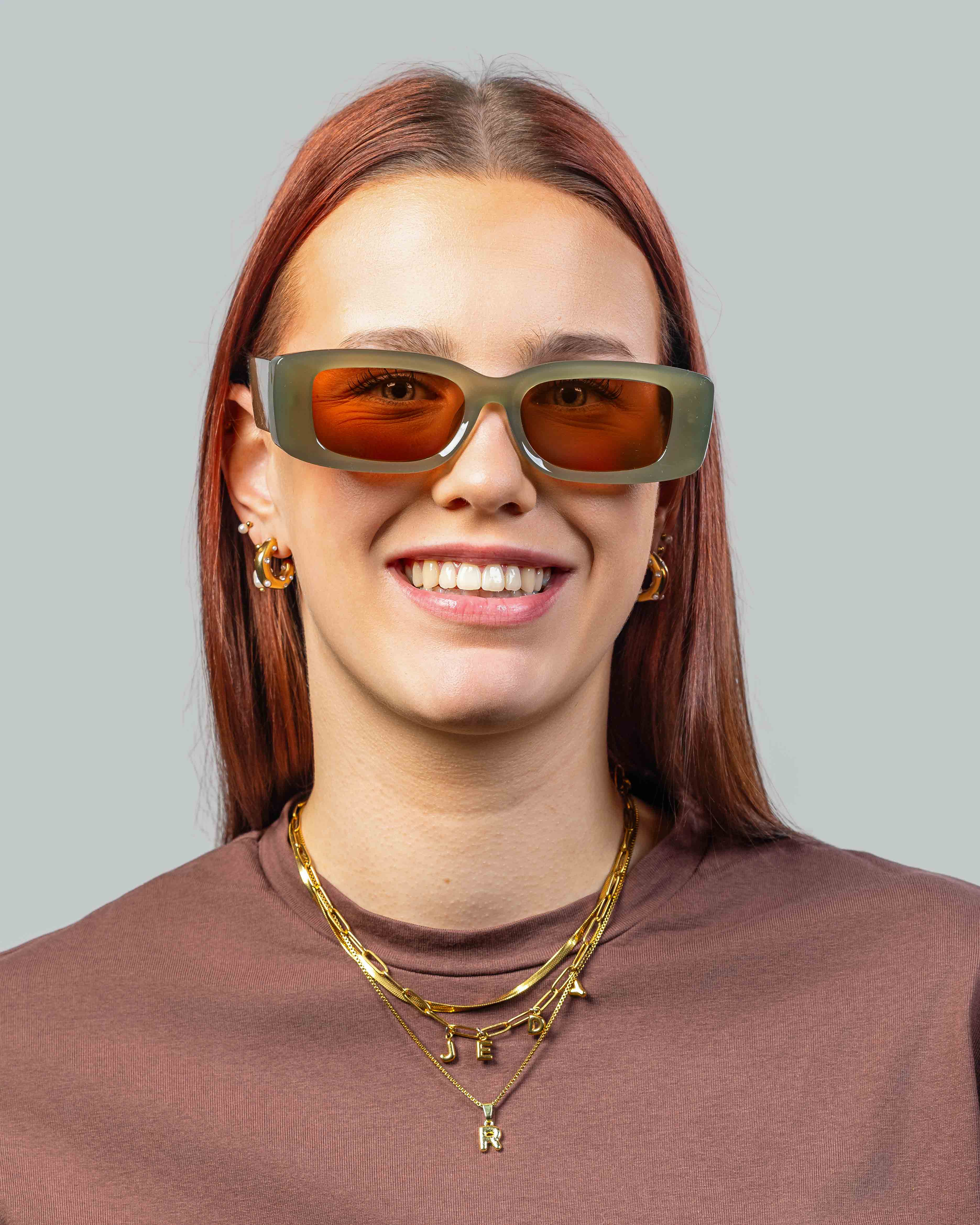 Vrouw met stijlvolle zonnebril, groen montuur en oranje glazen, perfect voor een trendy look.