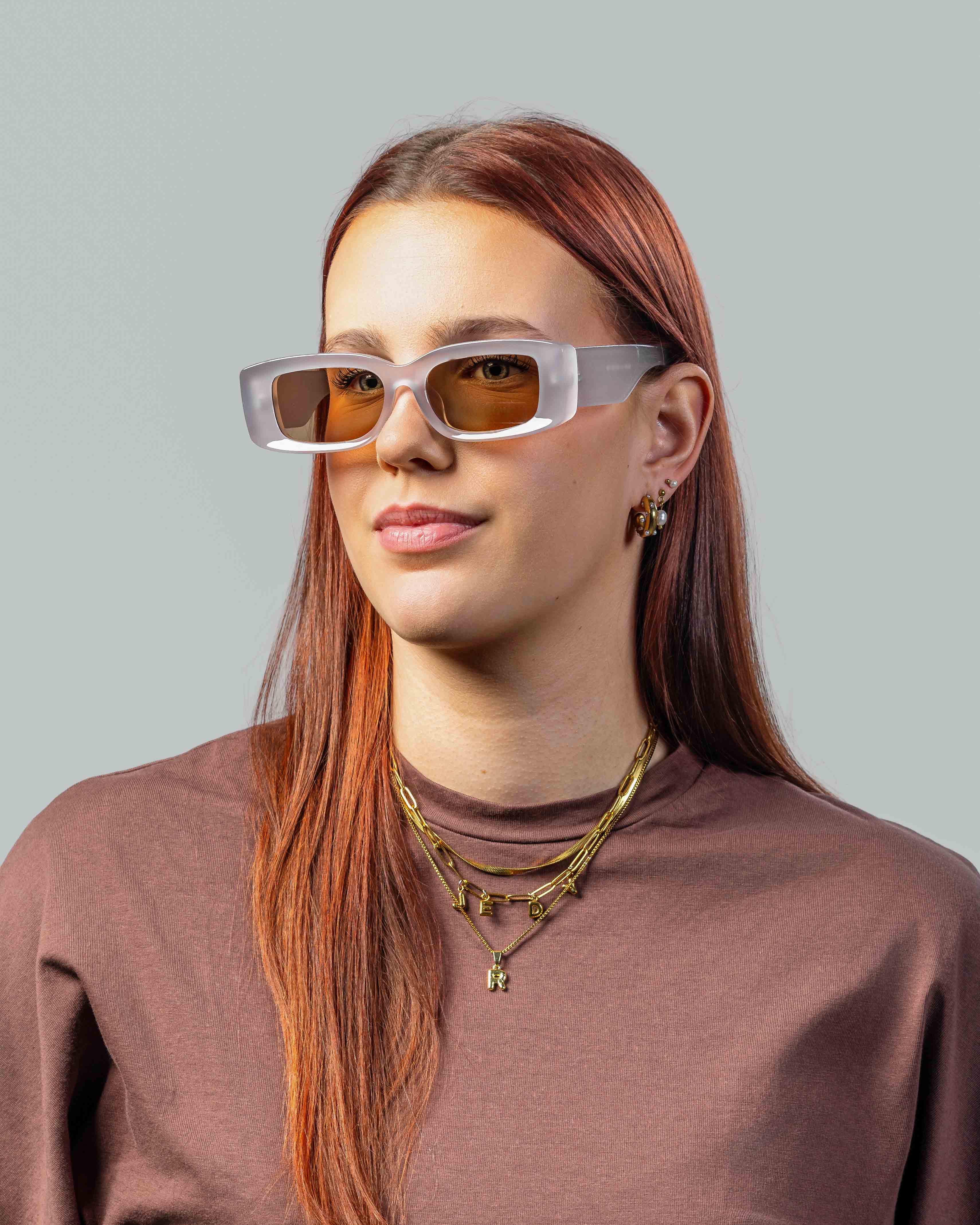 Vrouw met stijlvolle zonnebril met witte montuur en amber glazen, perfect voor een trendy look.