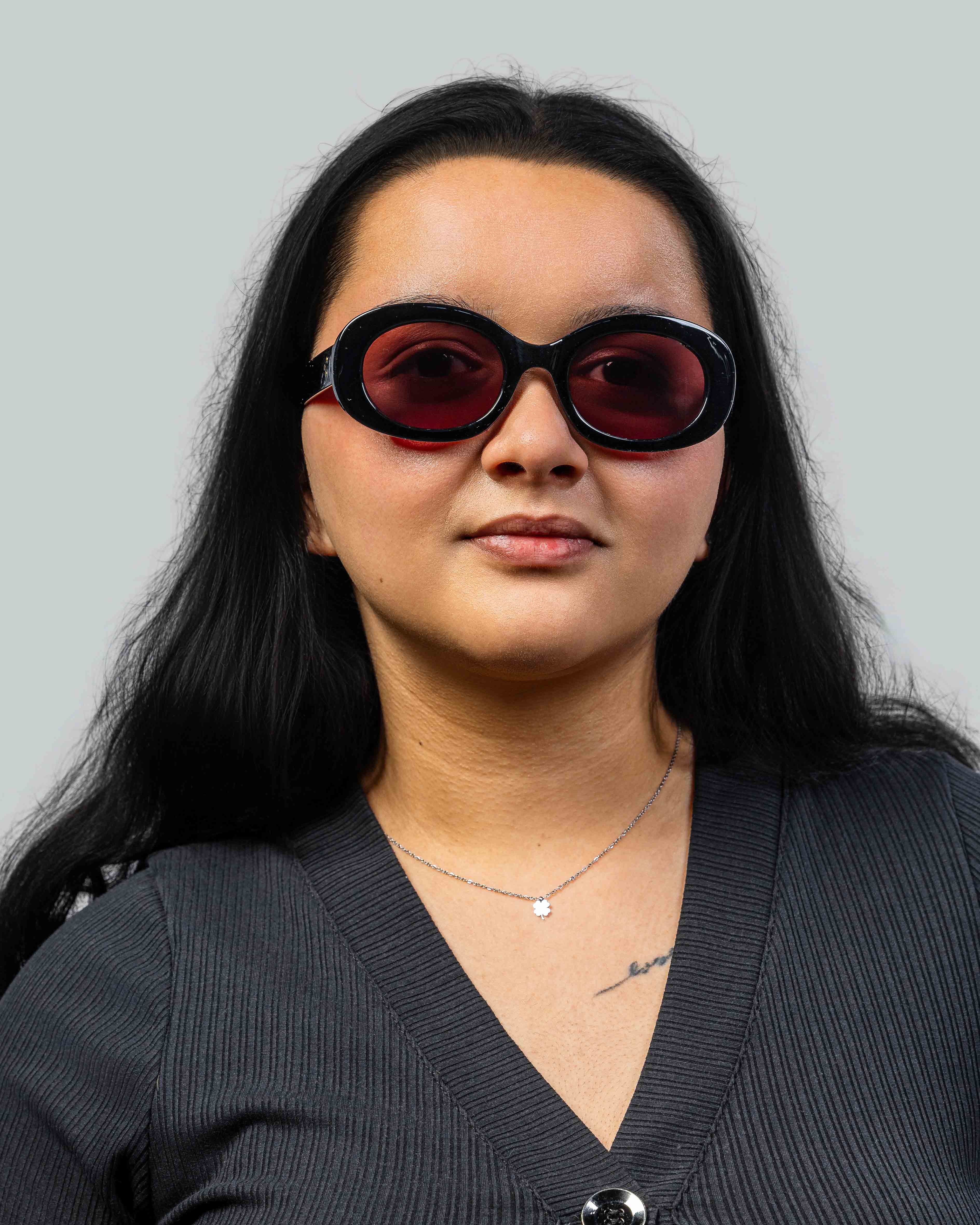 Vrouw met stijlvolle zonnebril met zwarte montuur en rode glazen, perfect voor een modieuze look.