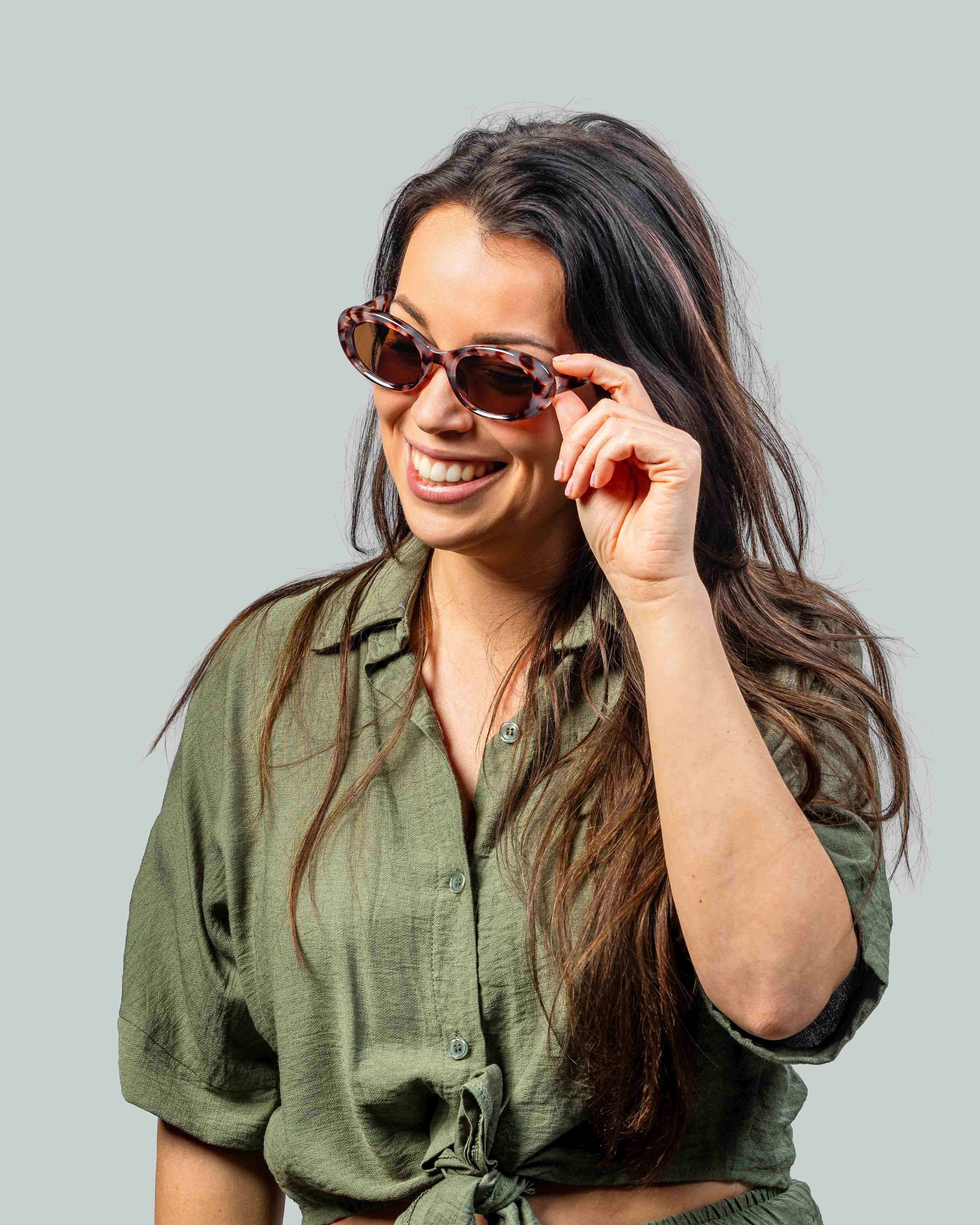 Vrouw met stijlvolle zonnebril en groene blouse, perfect voor zonnige dagen