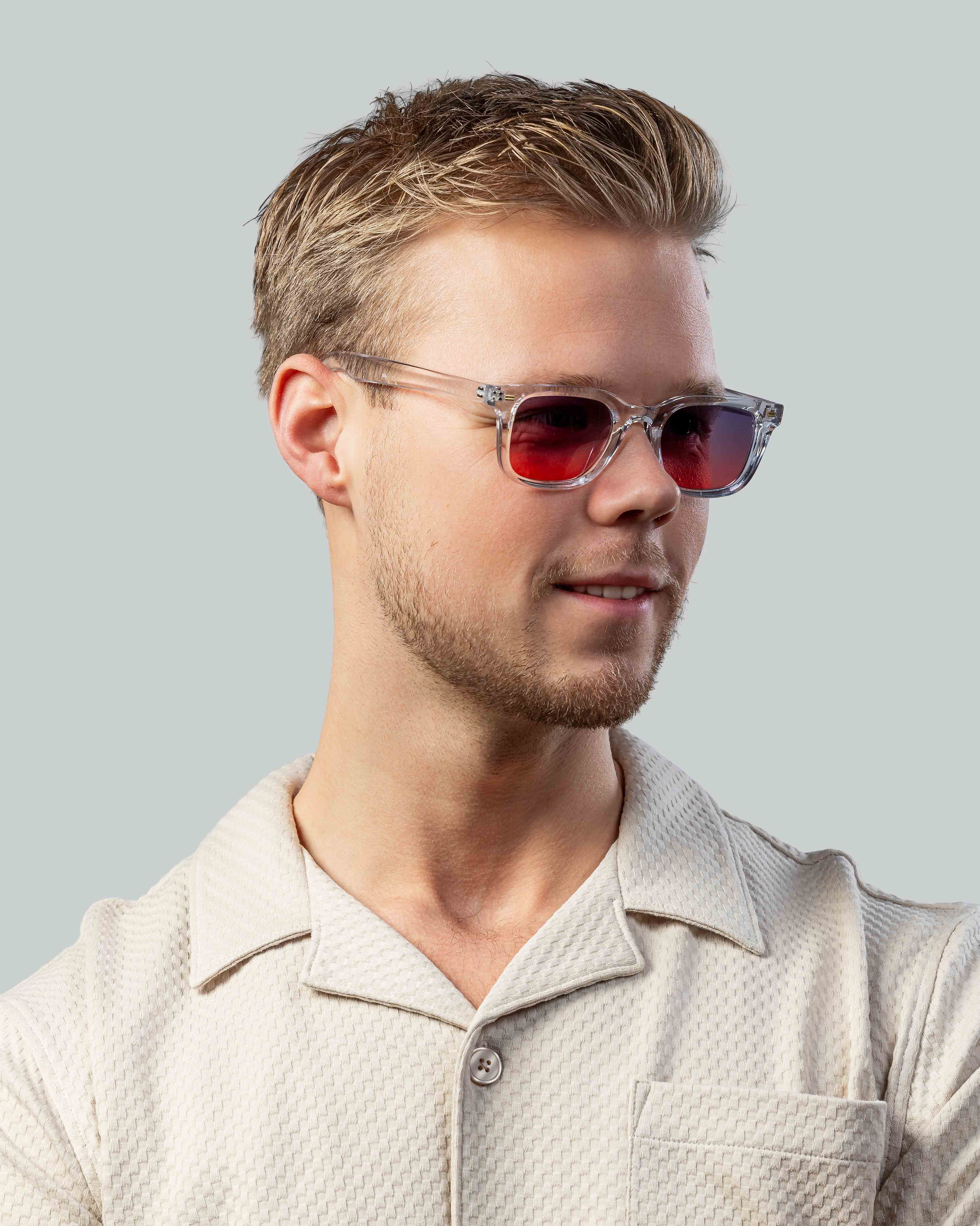 Stijlvolle zonnebril met rode glazen en transparante montuur, perfect voor een trendy look.