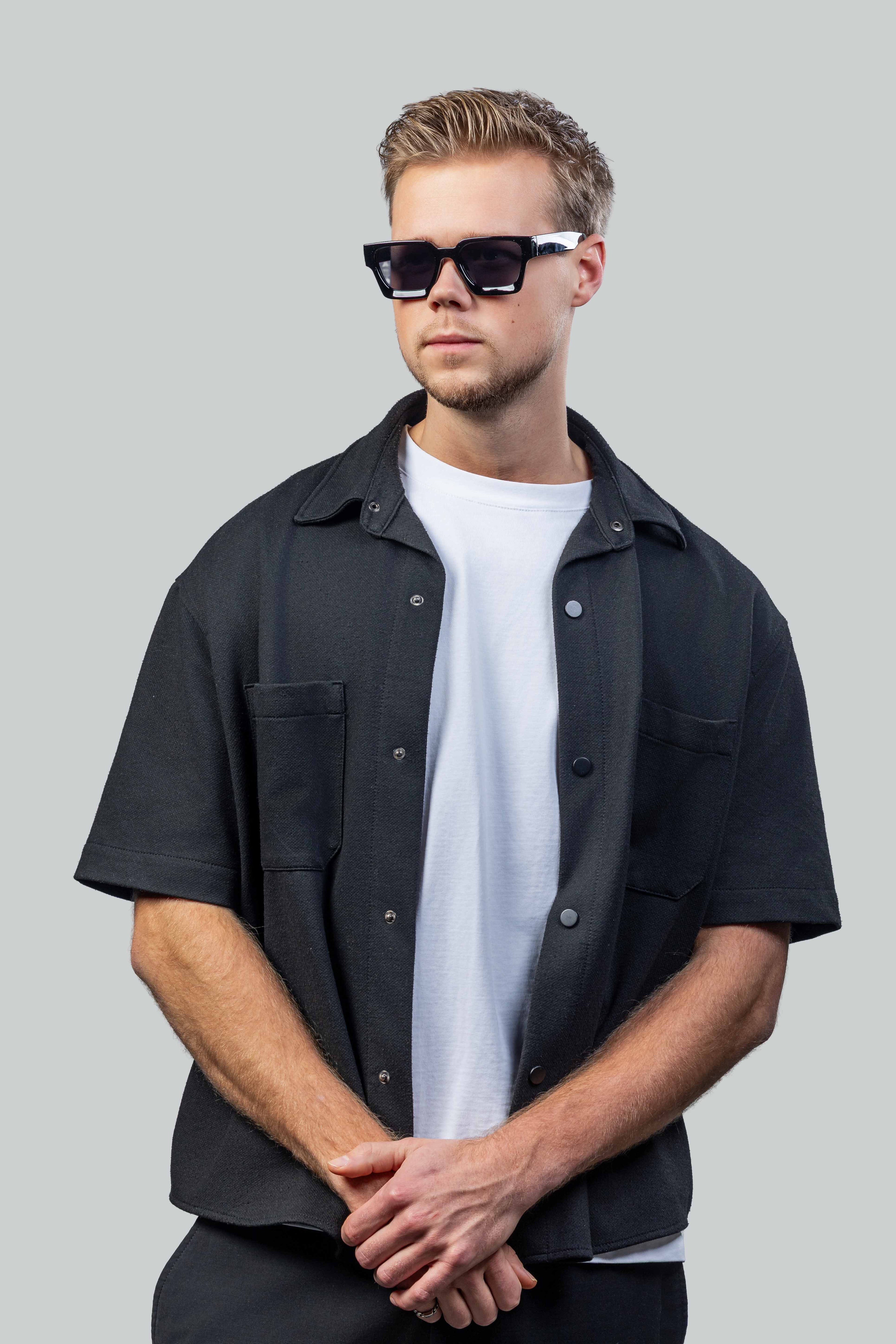 Man met stijlvolle zonnebril, zwart overhemd en wit T-shirt, perfect voor zomerse dagen.
