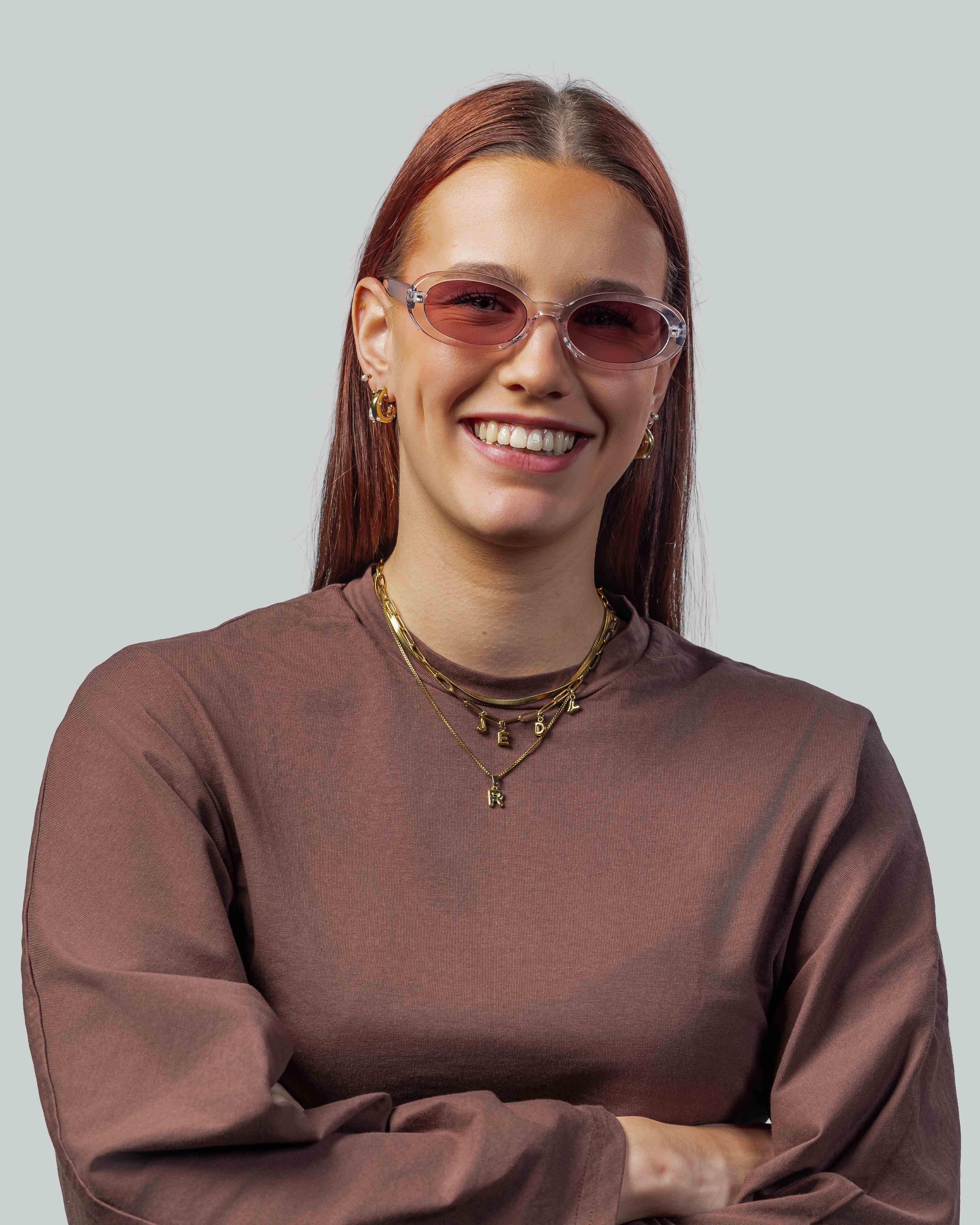 Vrouw met stijlvolle roze zonnebril en gouden sieraden, perfect voor een modieuze look.