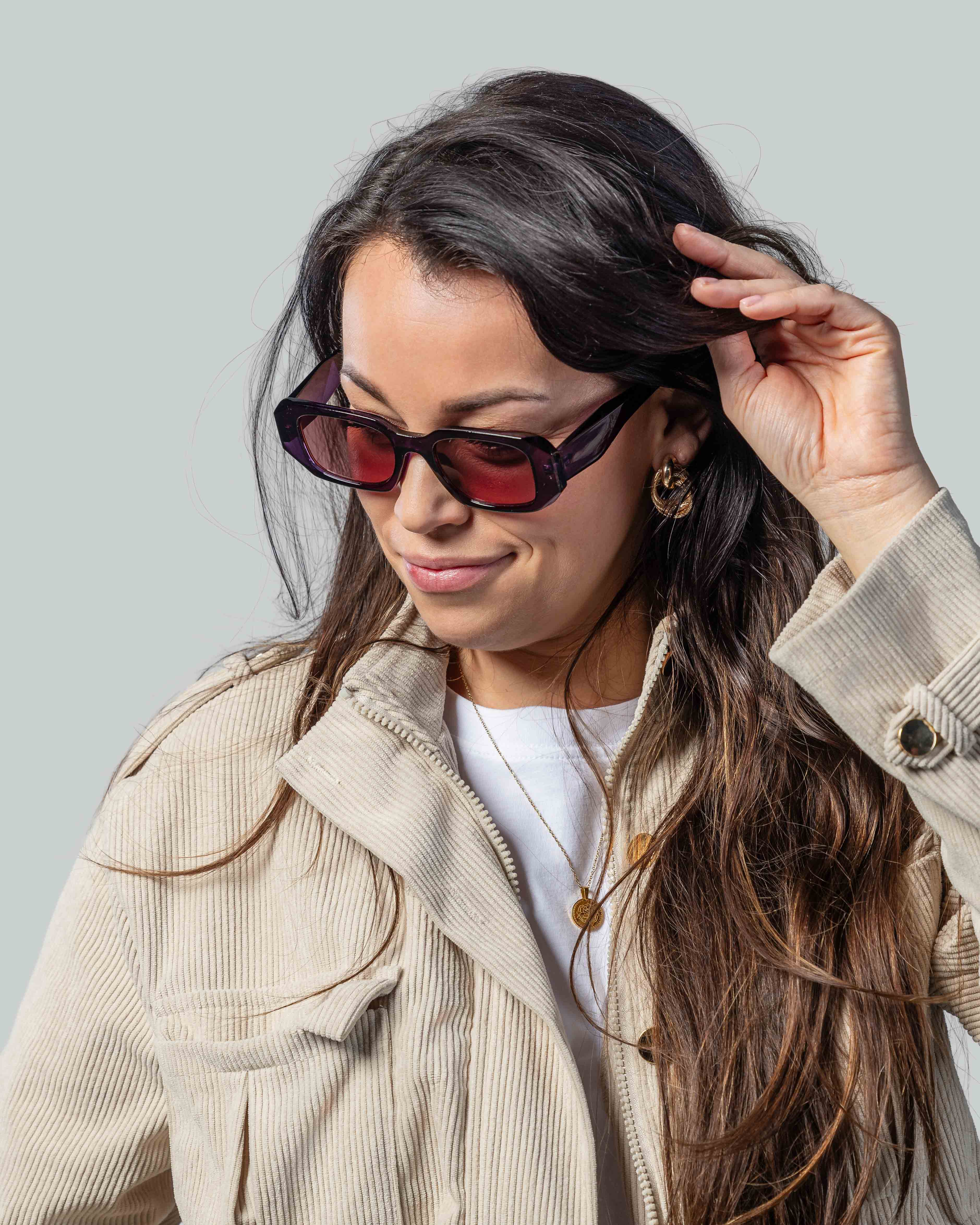 Vrouw met stijlvolle paarse zonnebril en beige jas, perfect voor een modieuze look
