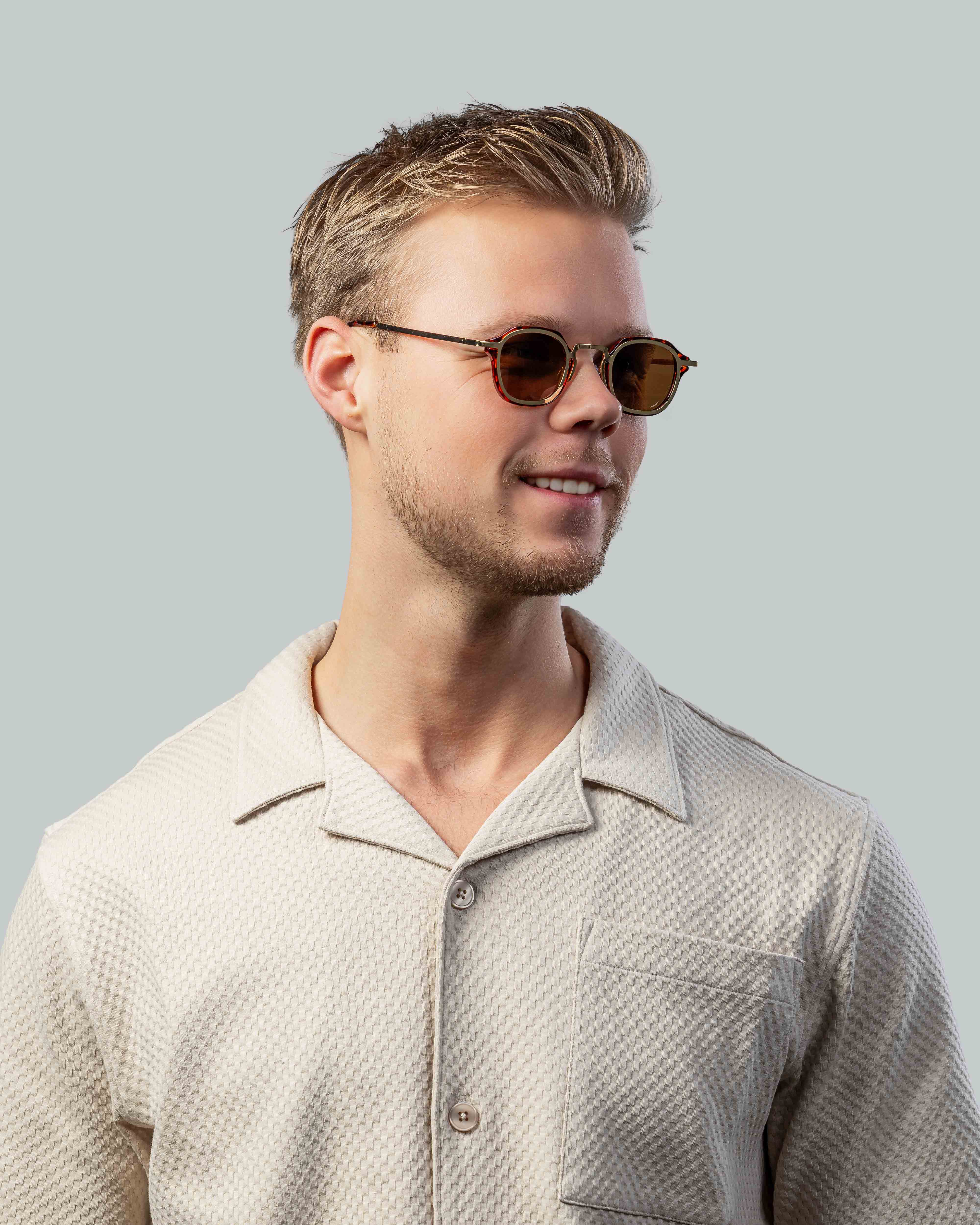 Man met stijlvolle zonnebril en lichte shirt, perfect voor zomerse dagen