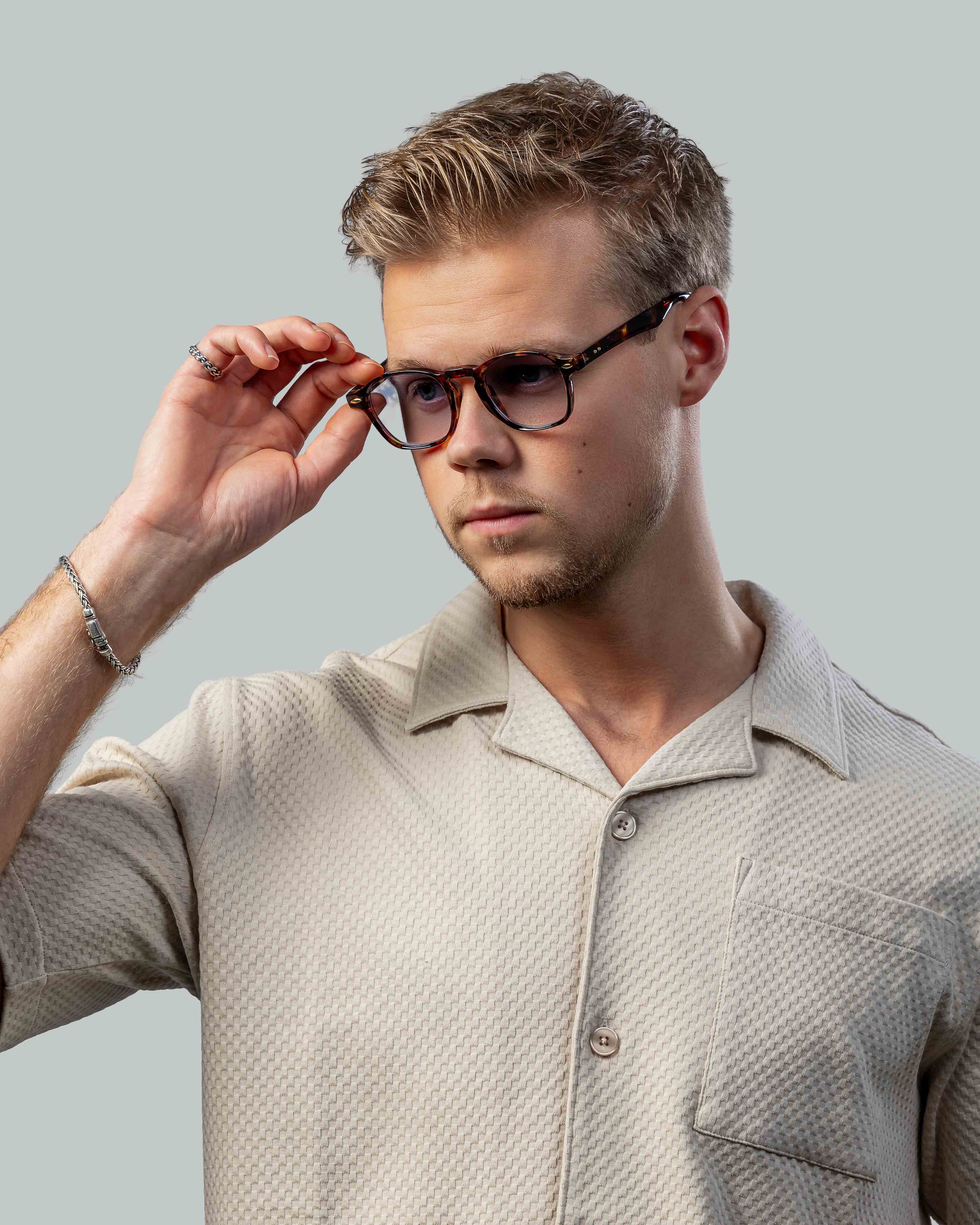 Stijlvolle bril met schildpadpatroon, gedragen door man in beige shirt