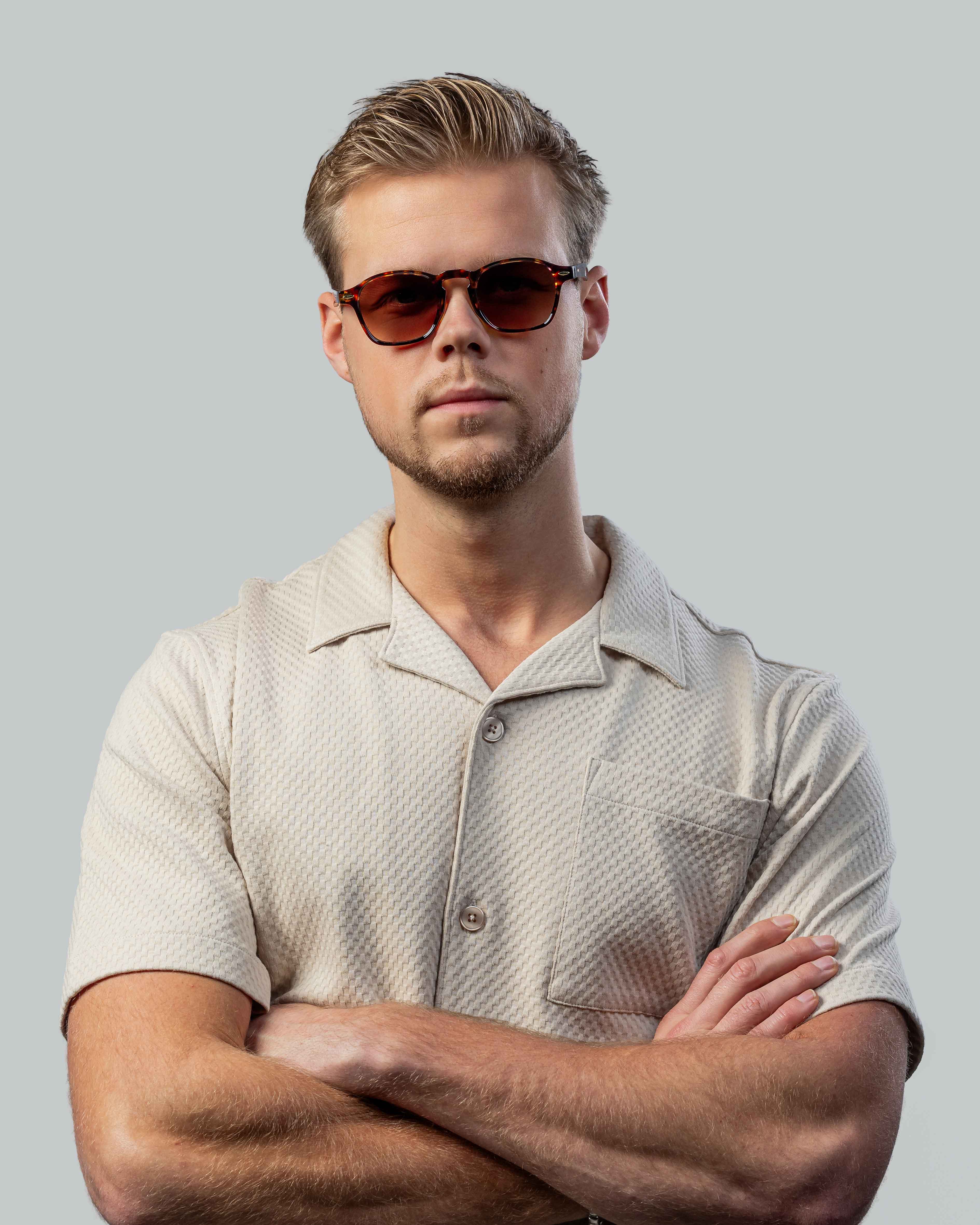 Man met stijlvolle zonnebril en beige shirt, perfect voor zomerse dagen