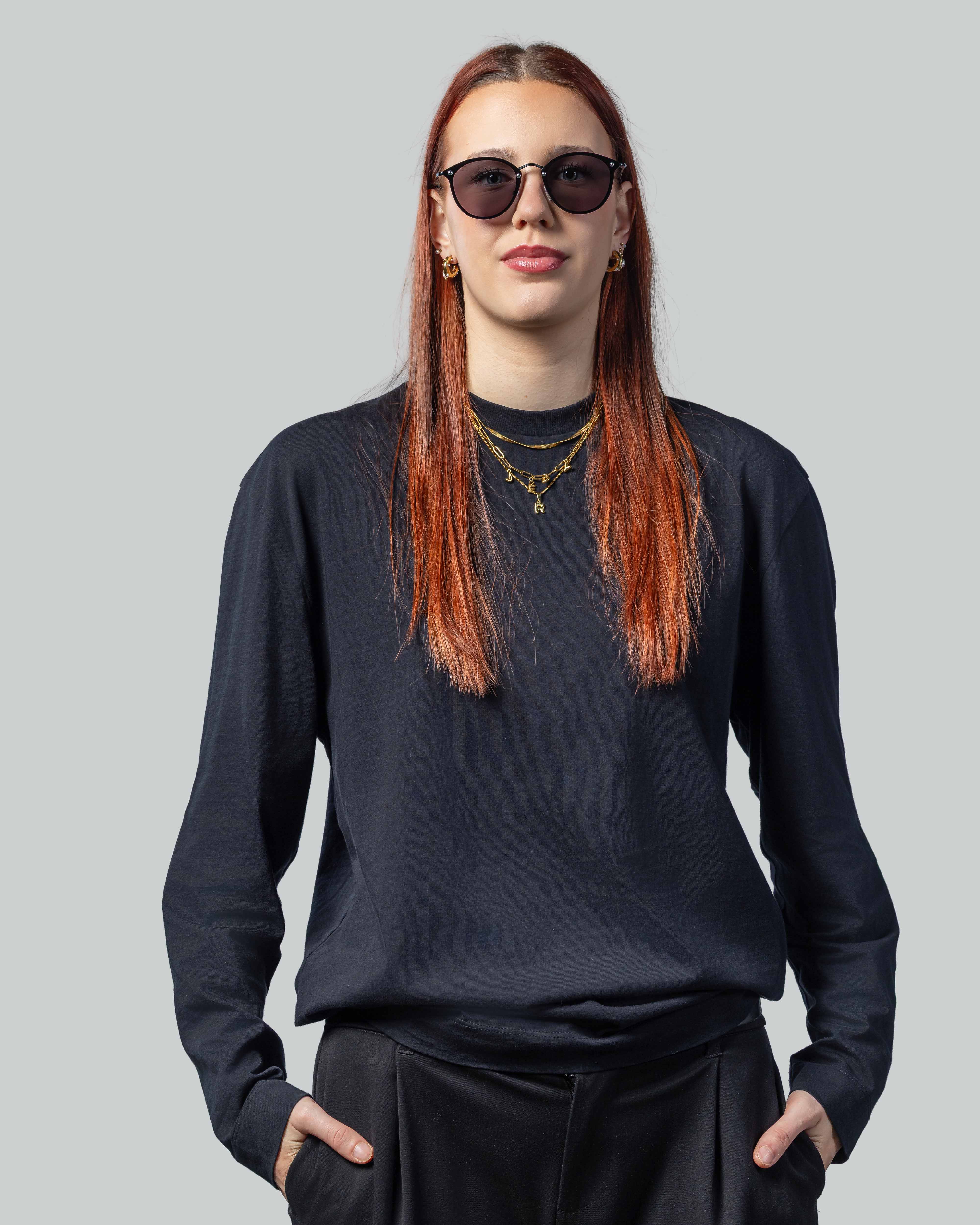 Vrouw met stijlvolle zonnebril, donkere outfit en gouden sieraden, perfect voor dagelijks dragen.