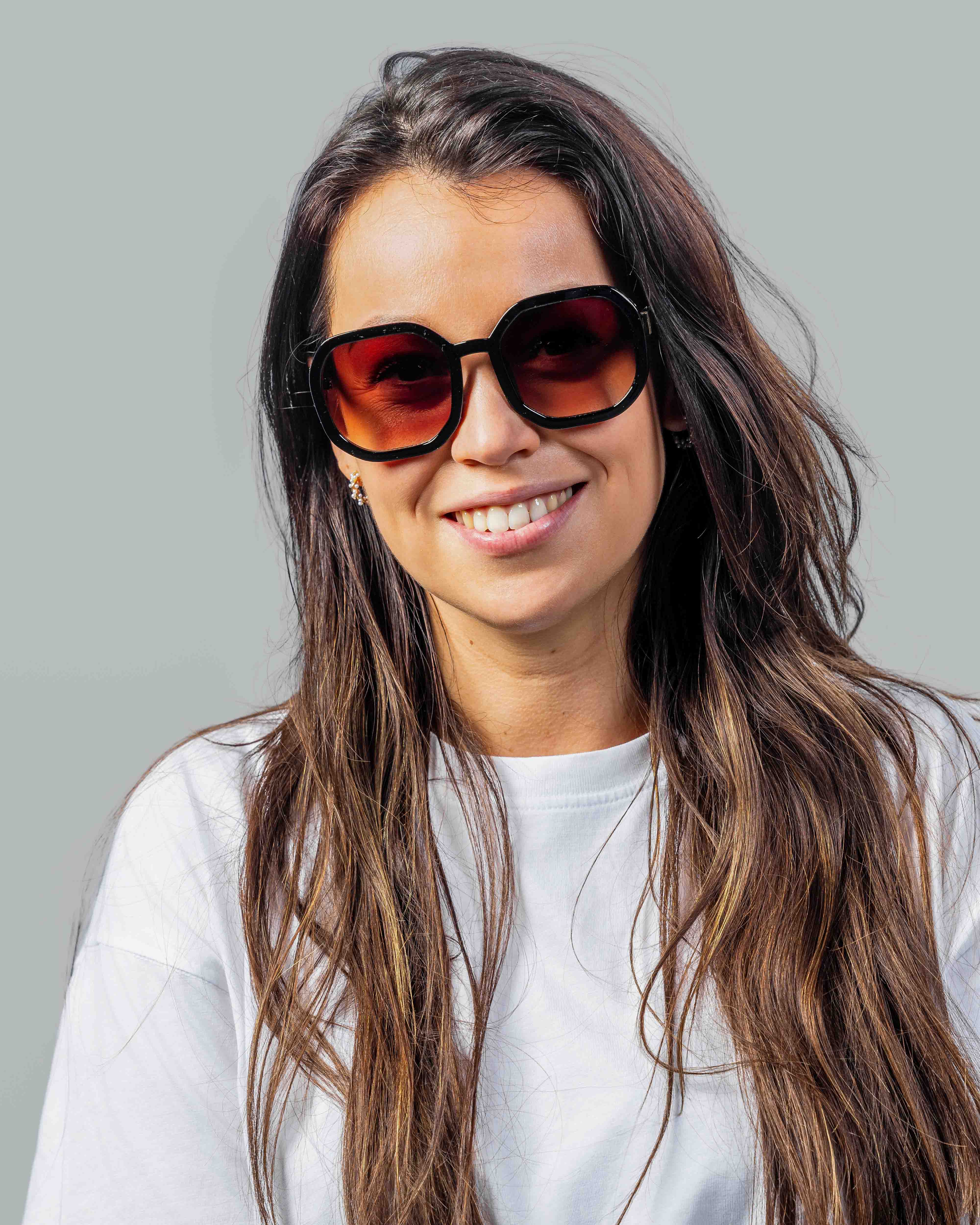 Vrouw met stijlvolle zonnebril, rode glazen en zwarte montuur, perfect voor zomerse dagen