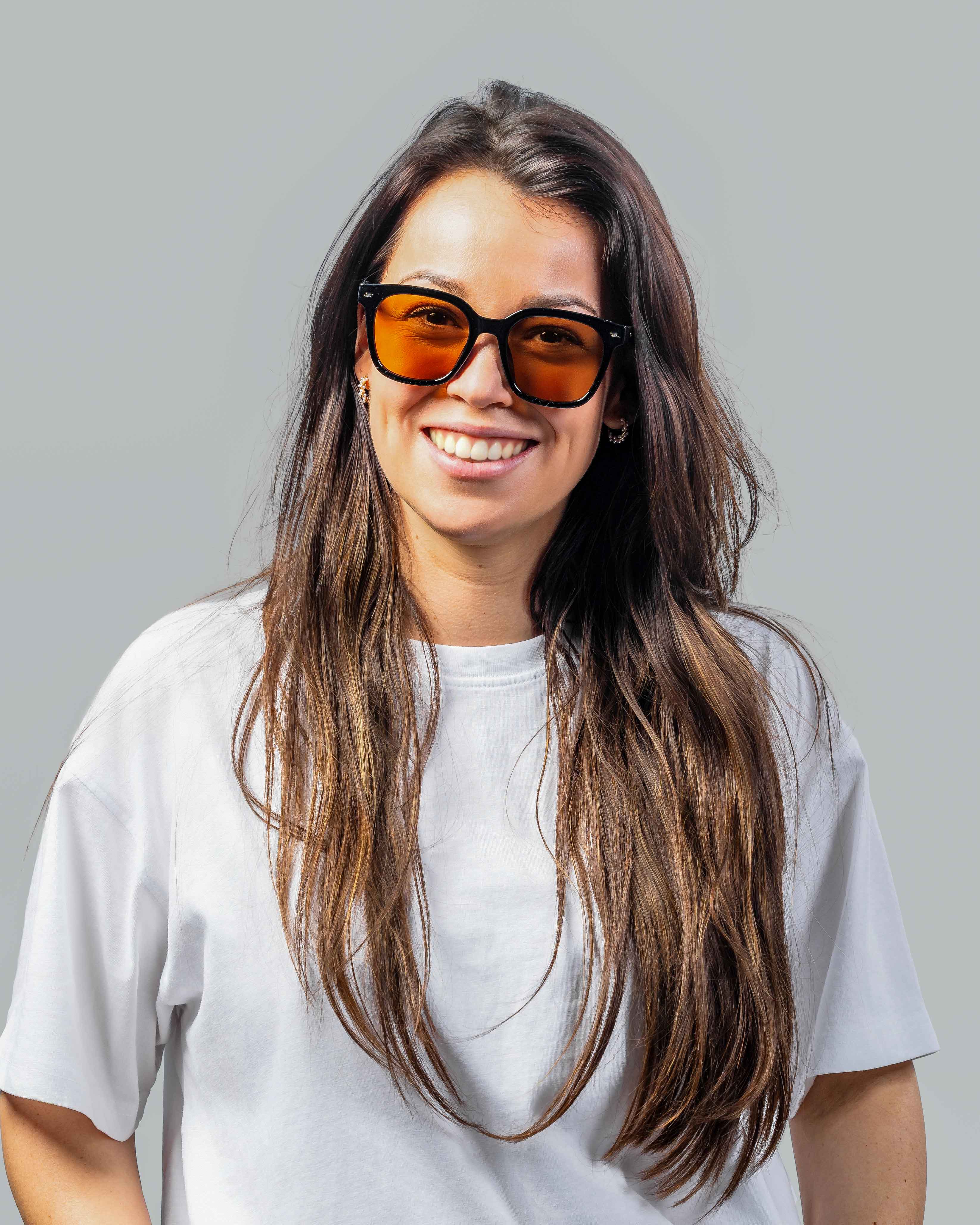 Vrouw met stijlvolle zonnebril met oranje glazen en zwarte montuur, perfect voor zonnige dagen.