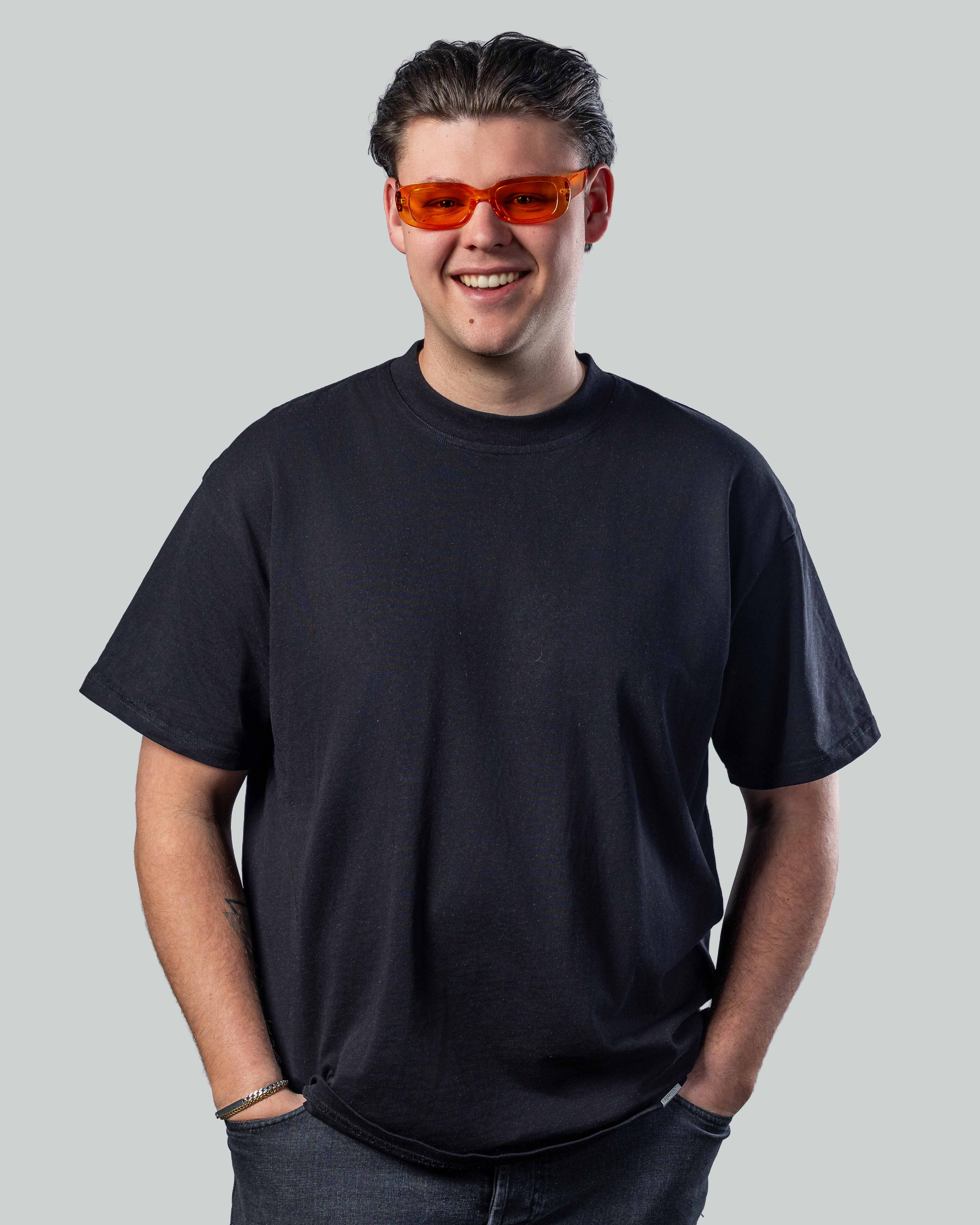 Man met oranje zonnebril en zwarte t-shirt, stijlvolle zonnebril voor een lage prijs