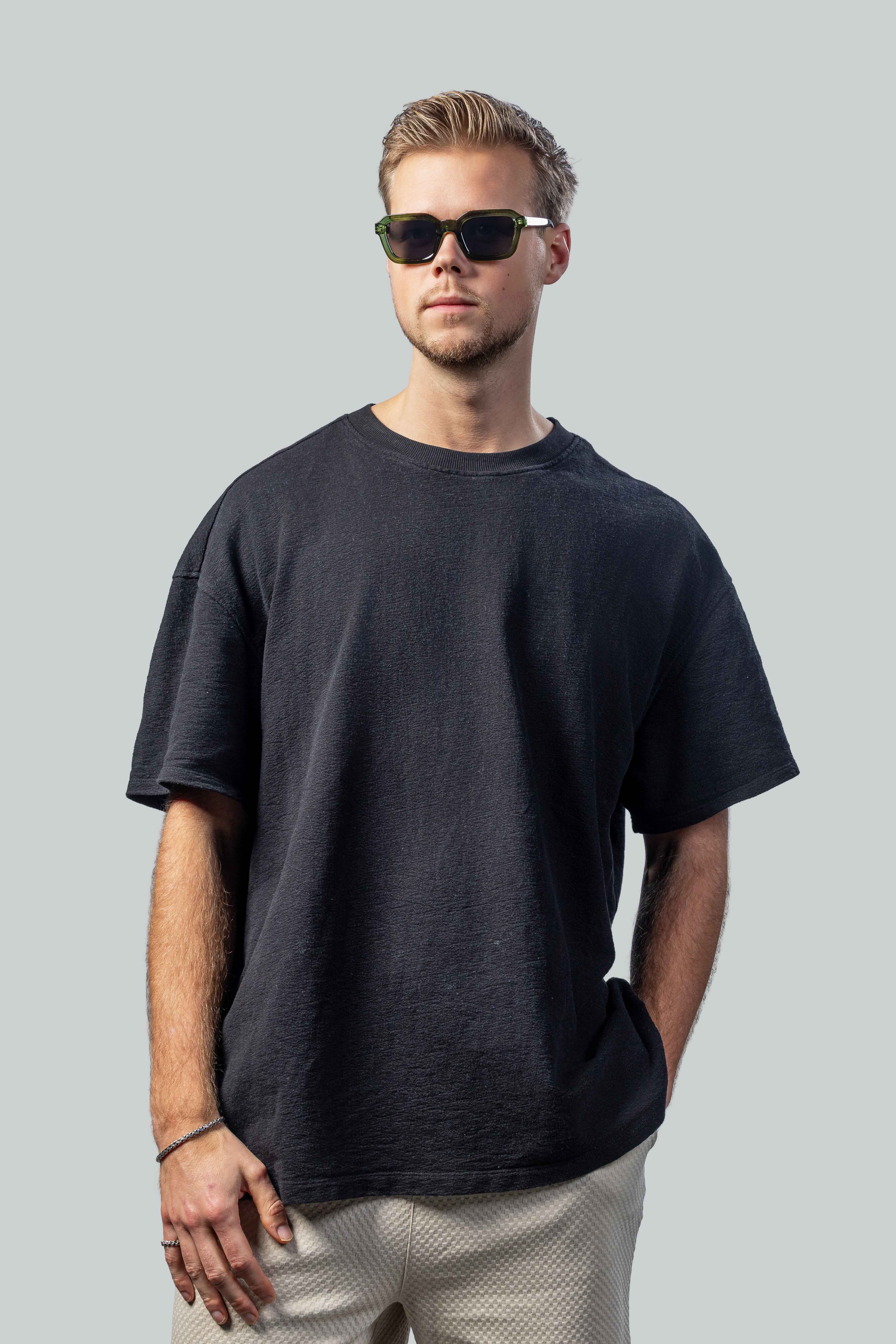 Man met stijlvolle groene zonnebril en donkere t-shirt, perfect voor zomerse dagen