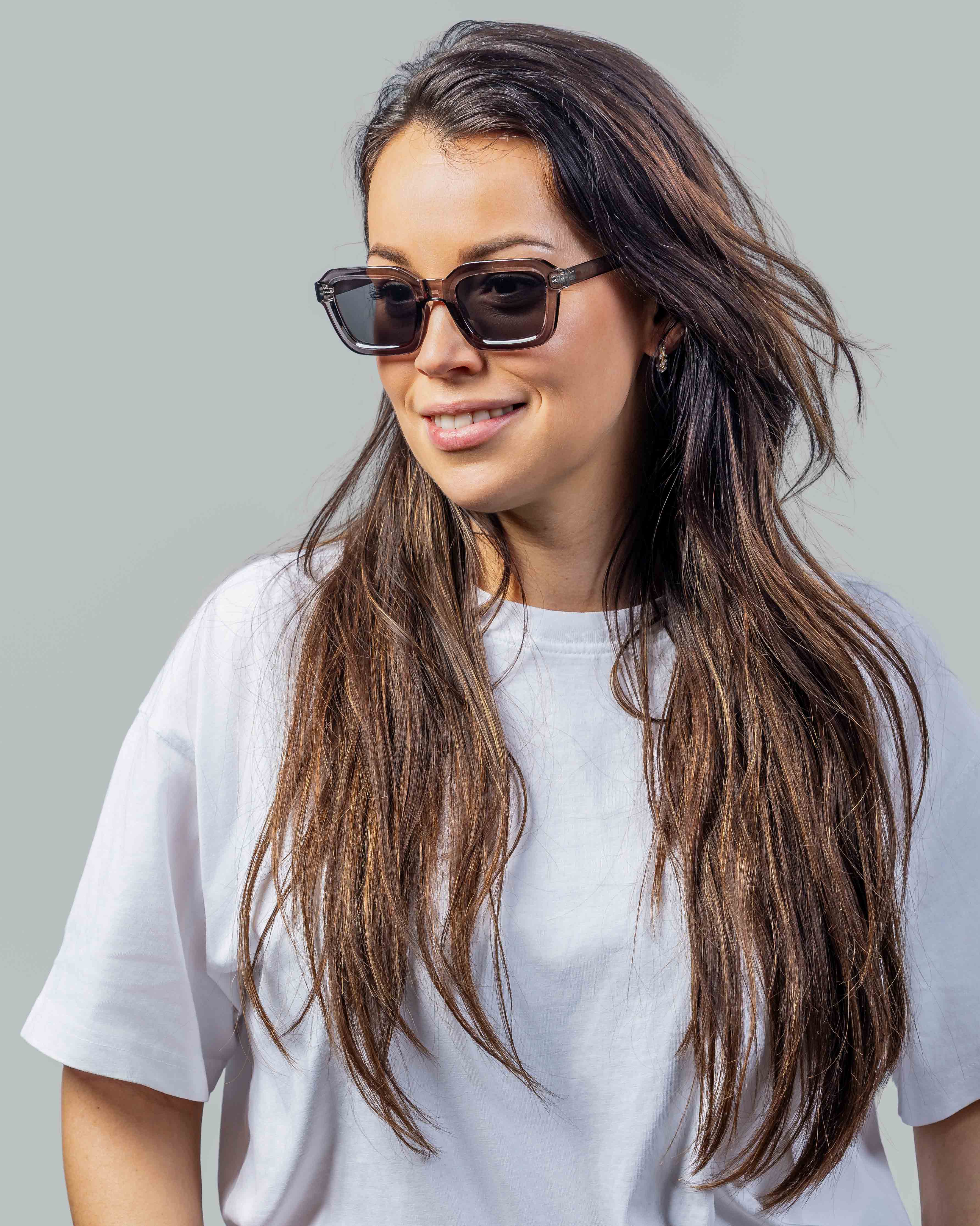 Vrouw met stijlvolle zonnebril, bruine glazen en witte t-shirt, perfect voor zonnige dagen