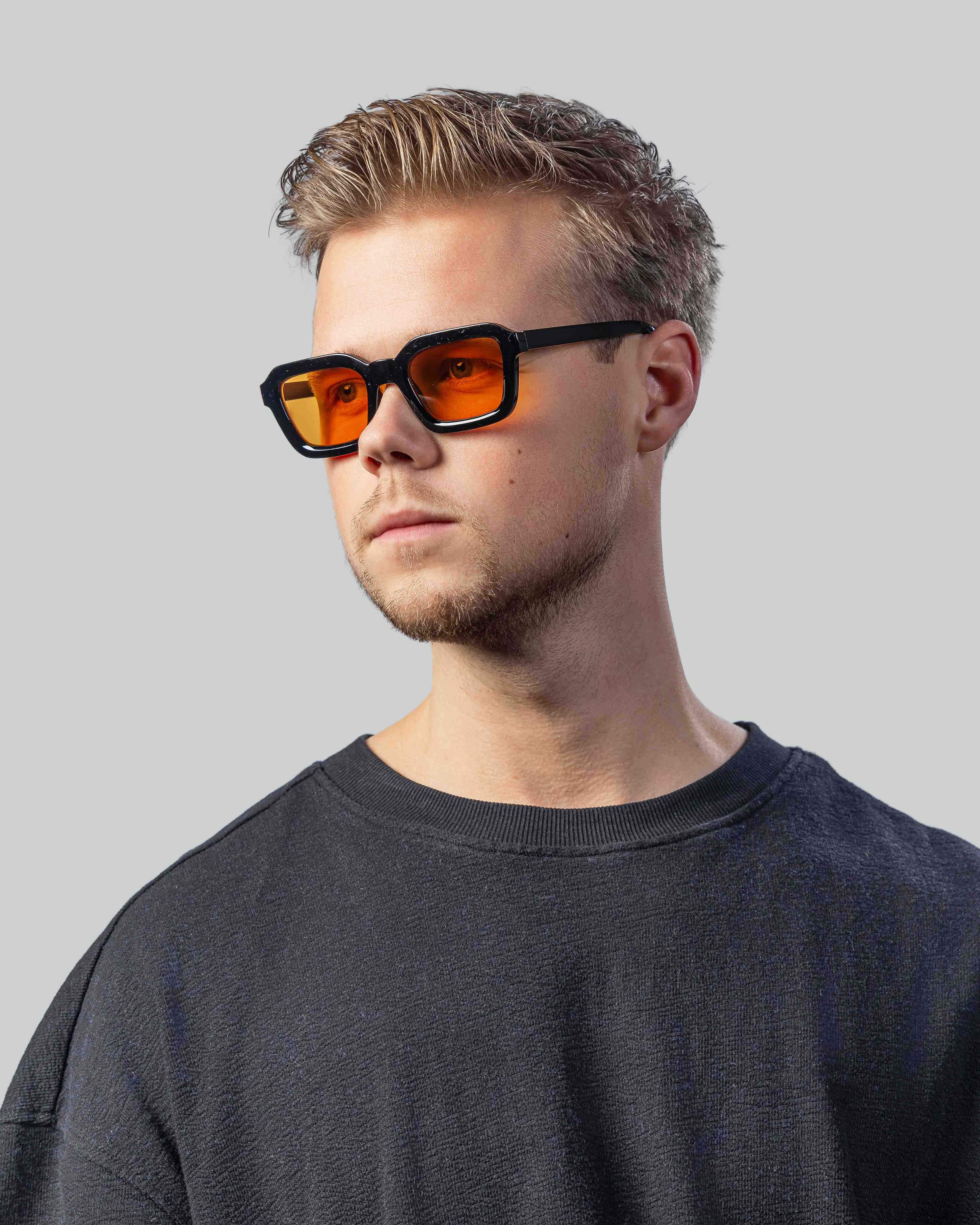Stijlvolle zonnebril met oranje glazen en zwarte montuur, perfect voor een moderne look.