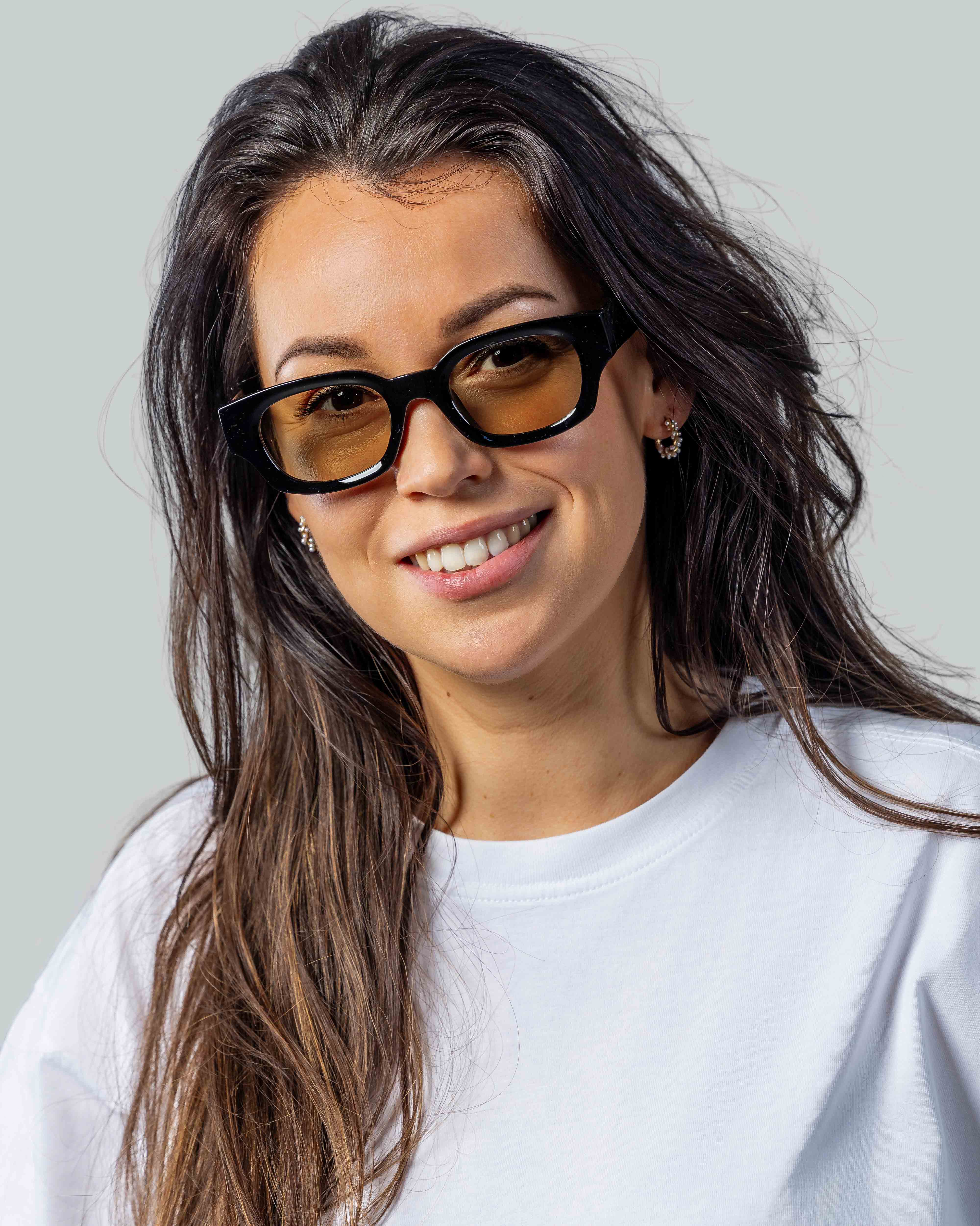 Vrouw met stijlvolle zwarte zonnebril en oranje glazen, perfect voor een trendy look.