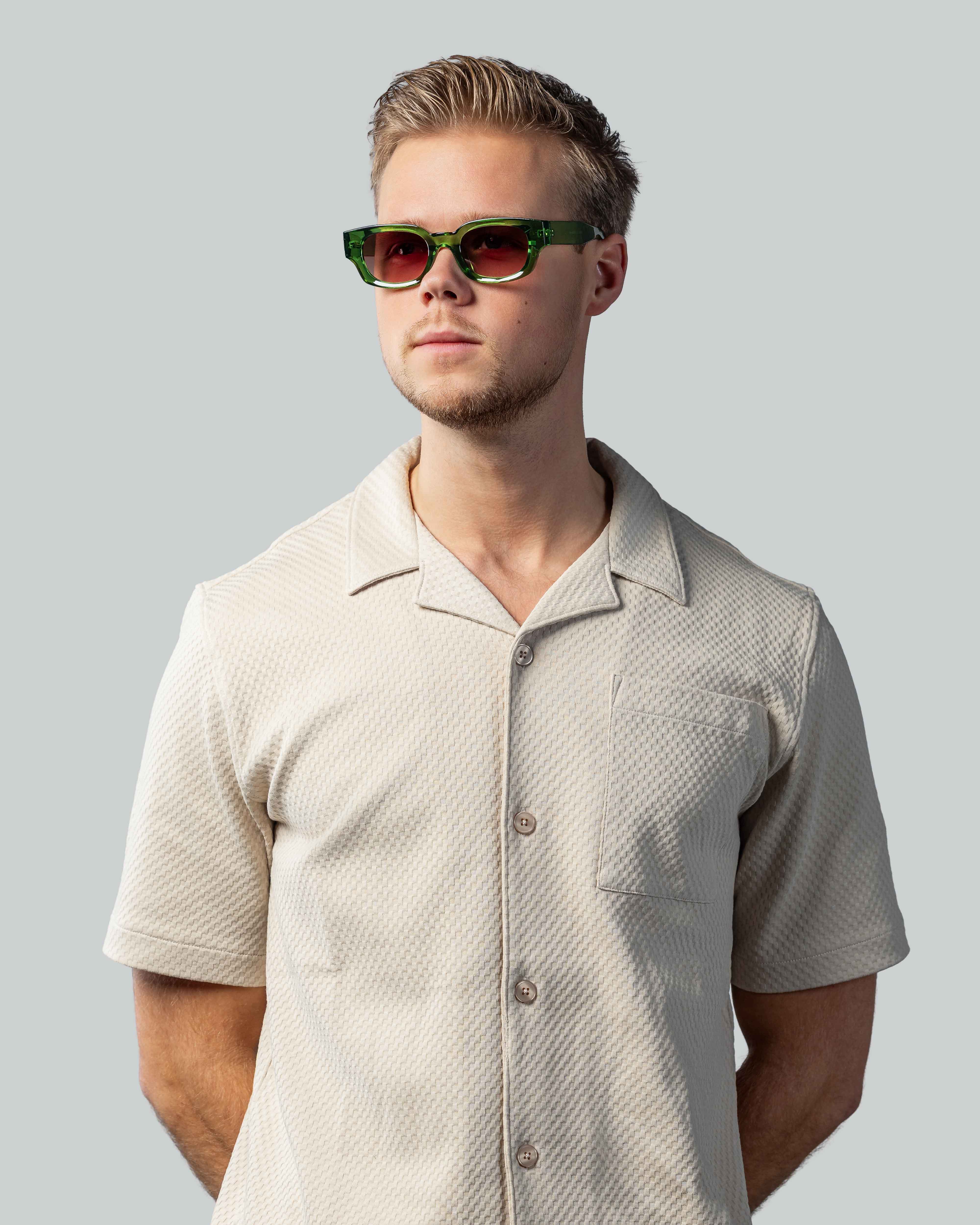 Man met groene zonnebril en beige overhemd, stijlvolle zonnebrillen voor een lage prijs