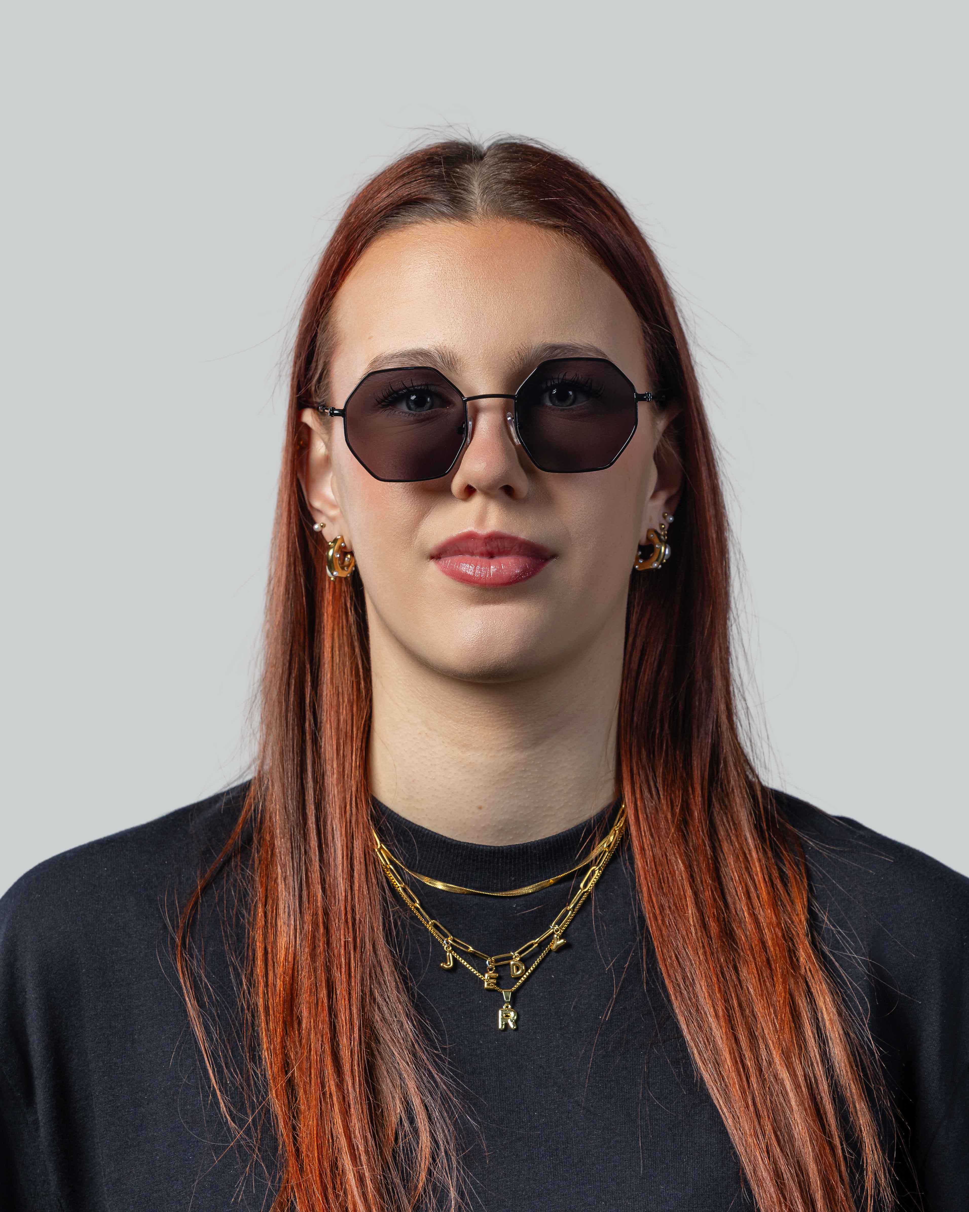 Stijlvolle zonnebril met octagonale glazen en gouden sieraden, perfect voor een modieuze look.