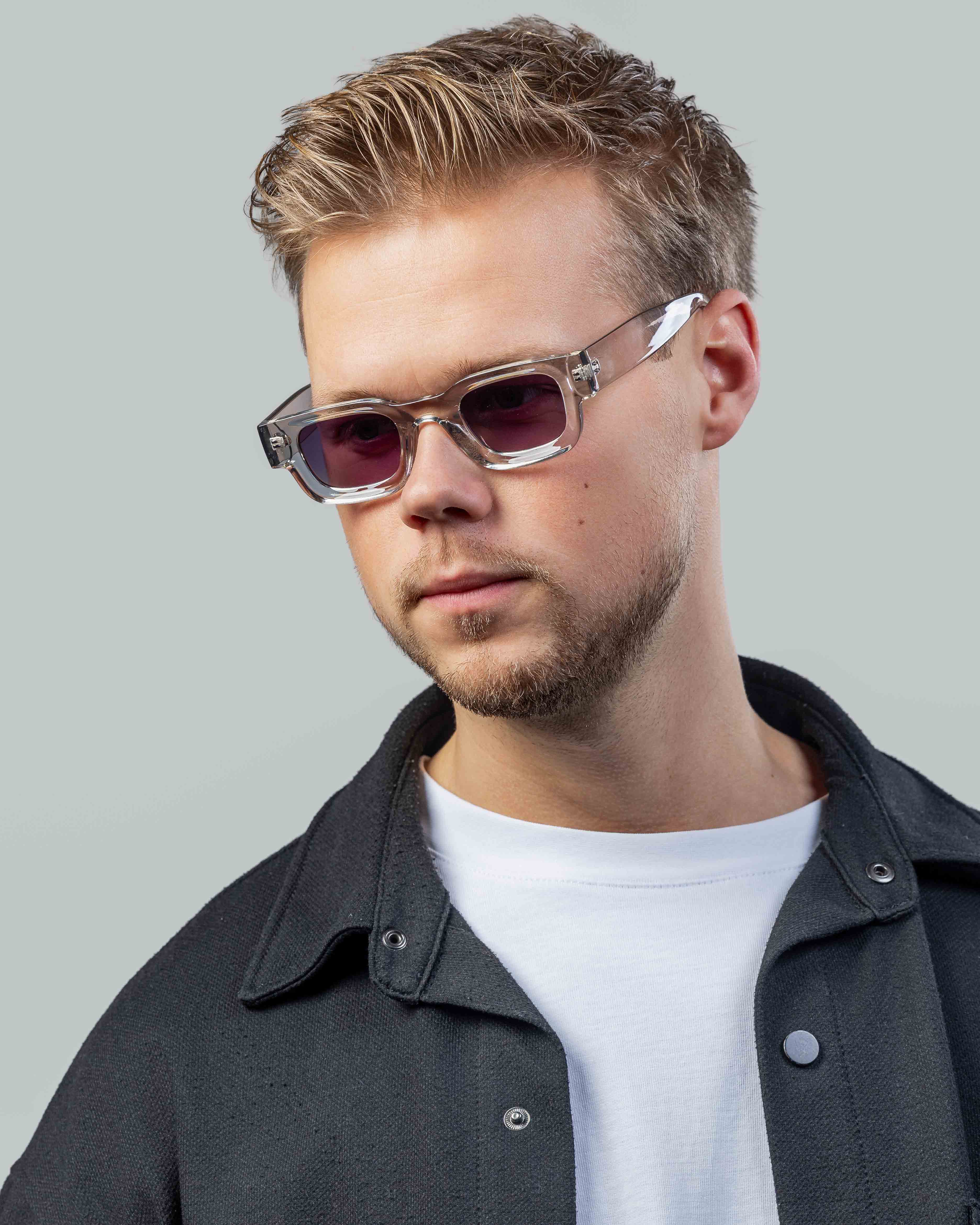 Stijlvolle zonnebril met transparant montuur en roze glazen, gedragen door man in casual outfit