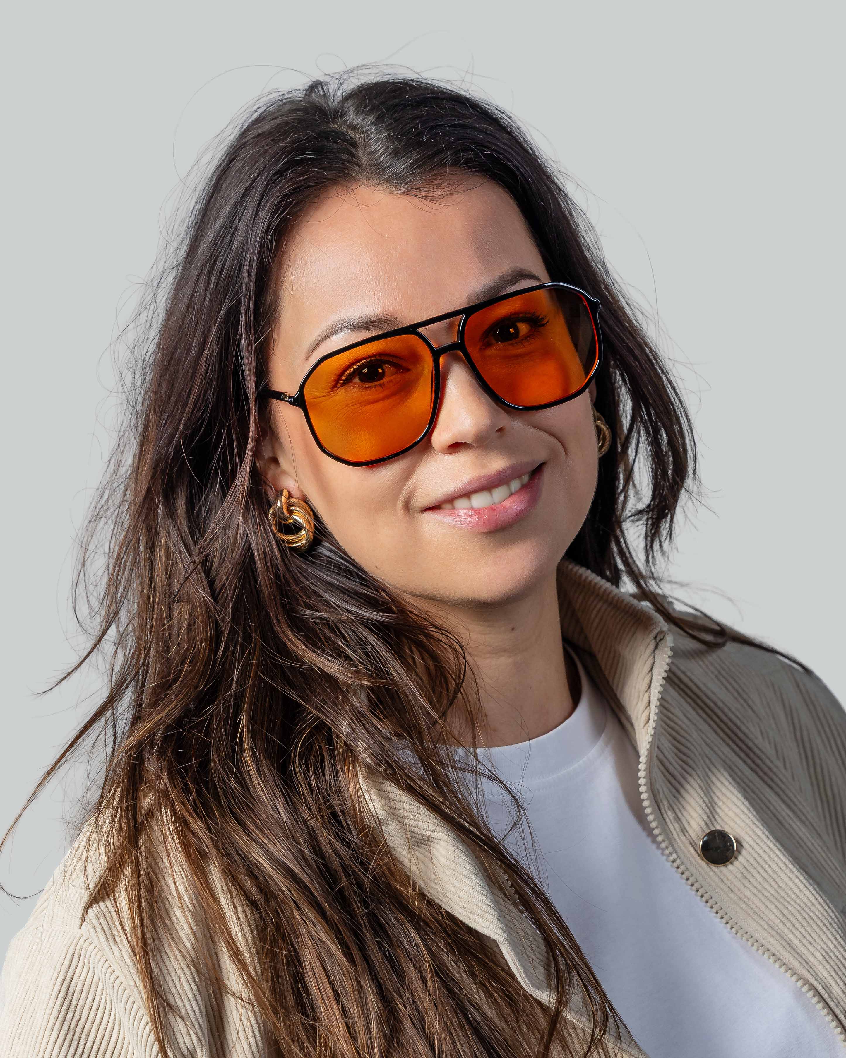 Vrouw met stijlvolle zonnebril met oranje glazen en zwarte montuur, perfect voor een modieuze look.