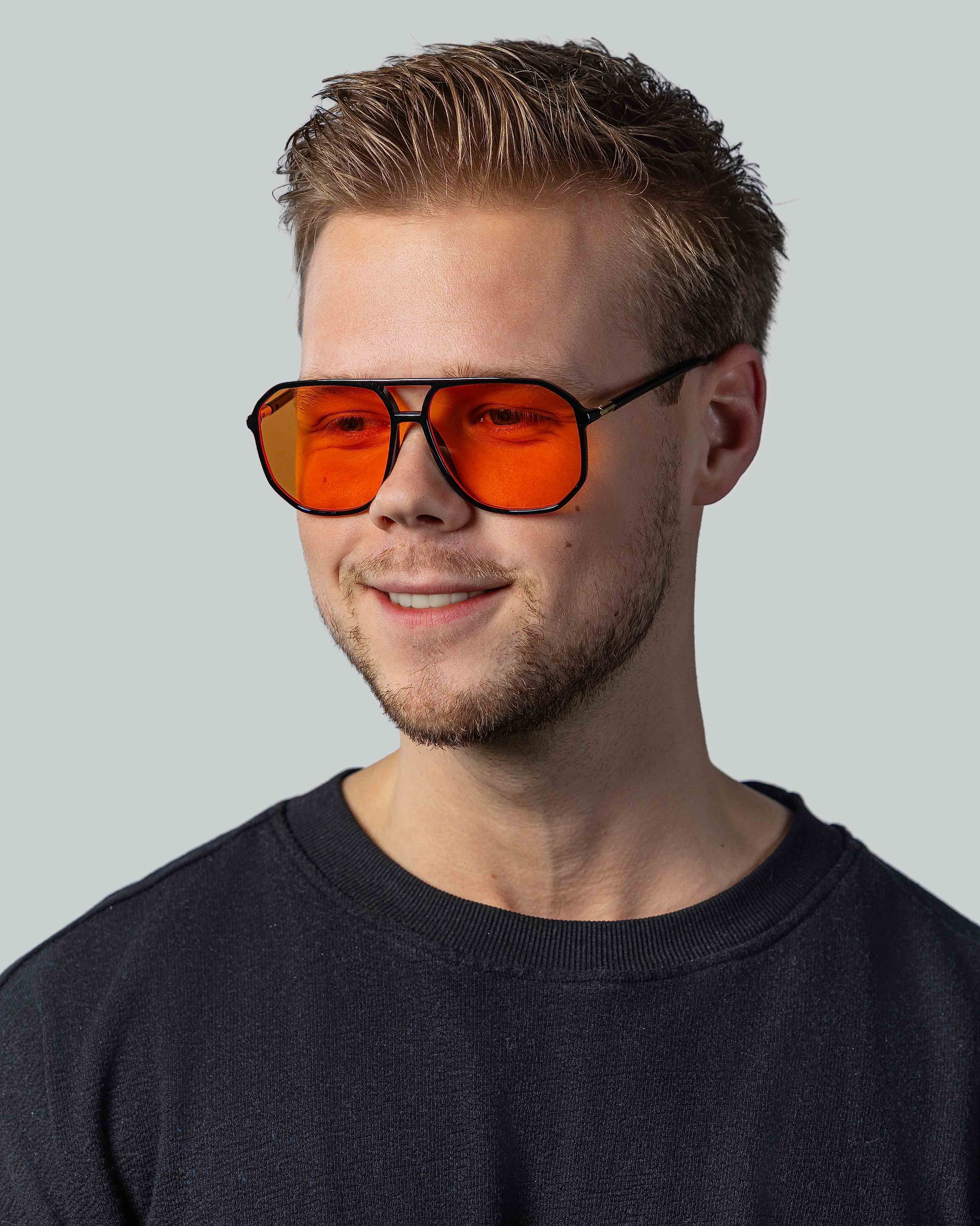 Man met stijlvolle zonnebril met oranje glazen en zwarte montuur