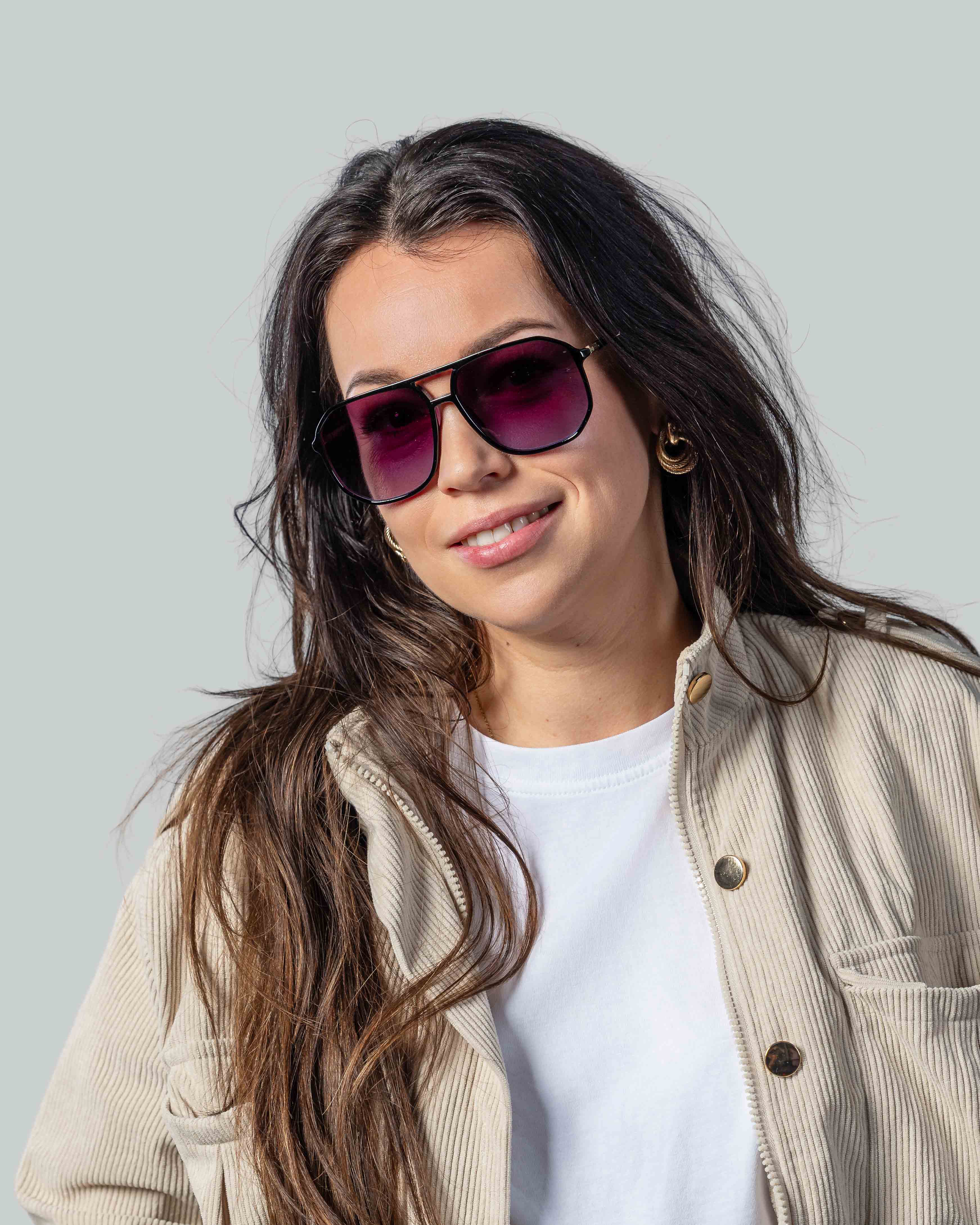Vrouw met stijlvolle zonnebril, paarse glazen en zwarte montuur, perfect voor een modieuze look.