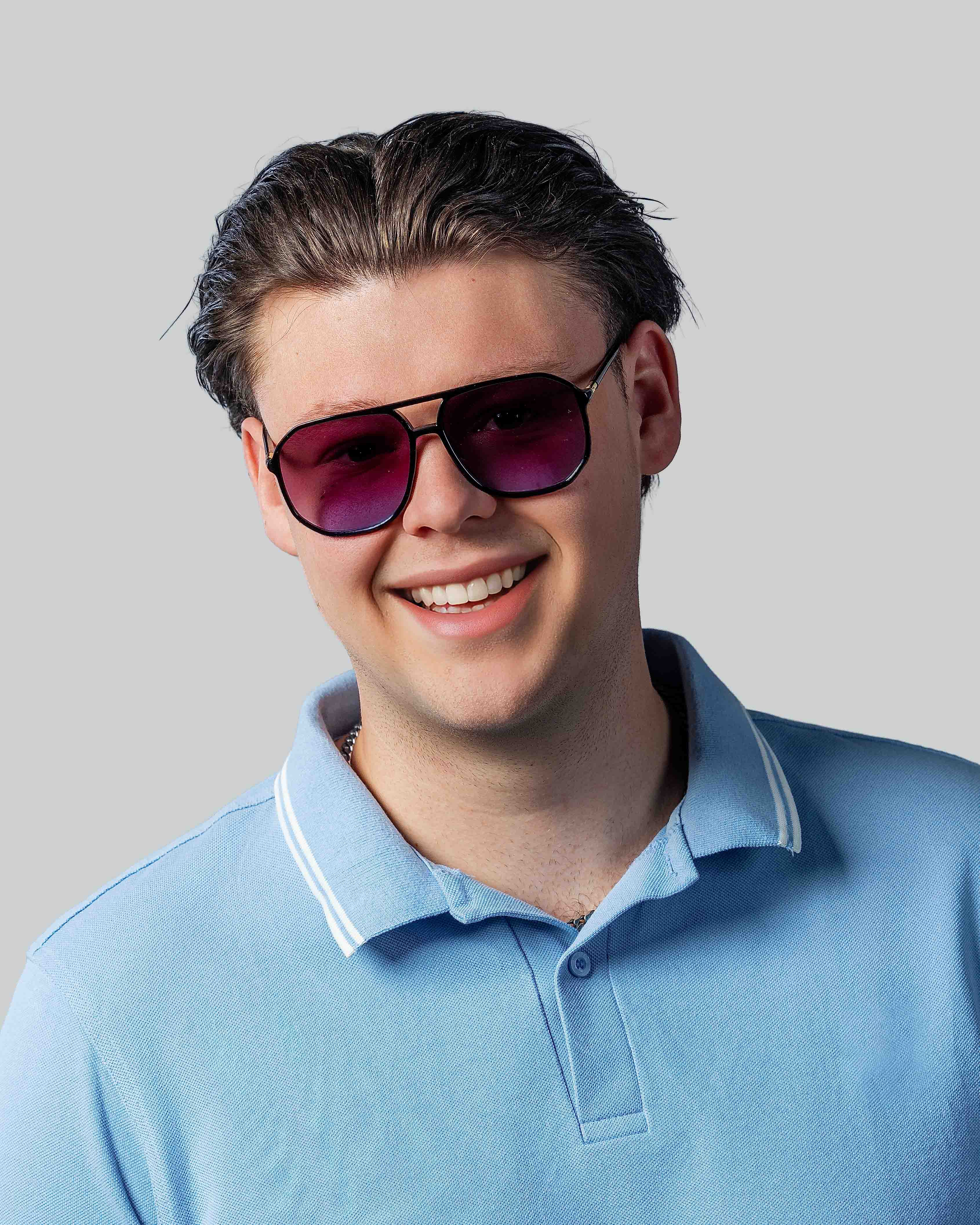 Stijlvolle zonnebril met paarse glazen en zwarte montuur, gedragen door man in blauw poloshirt