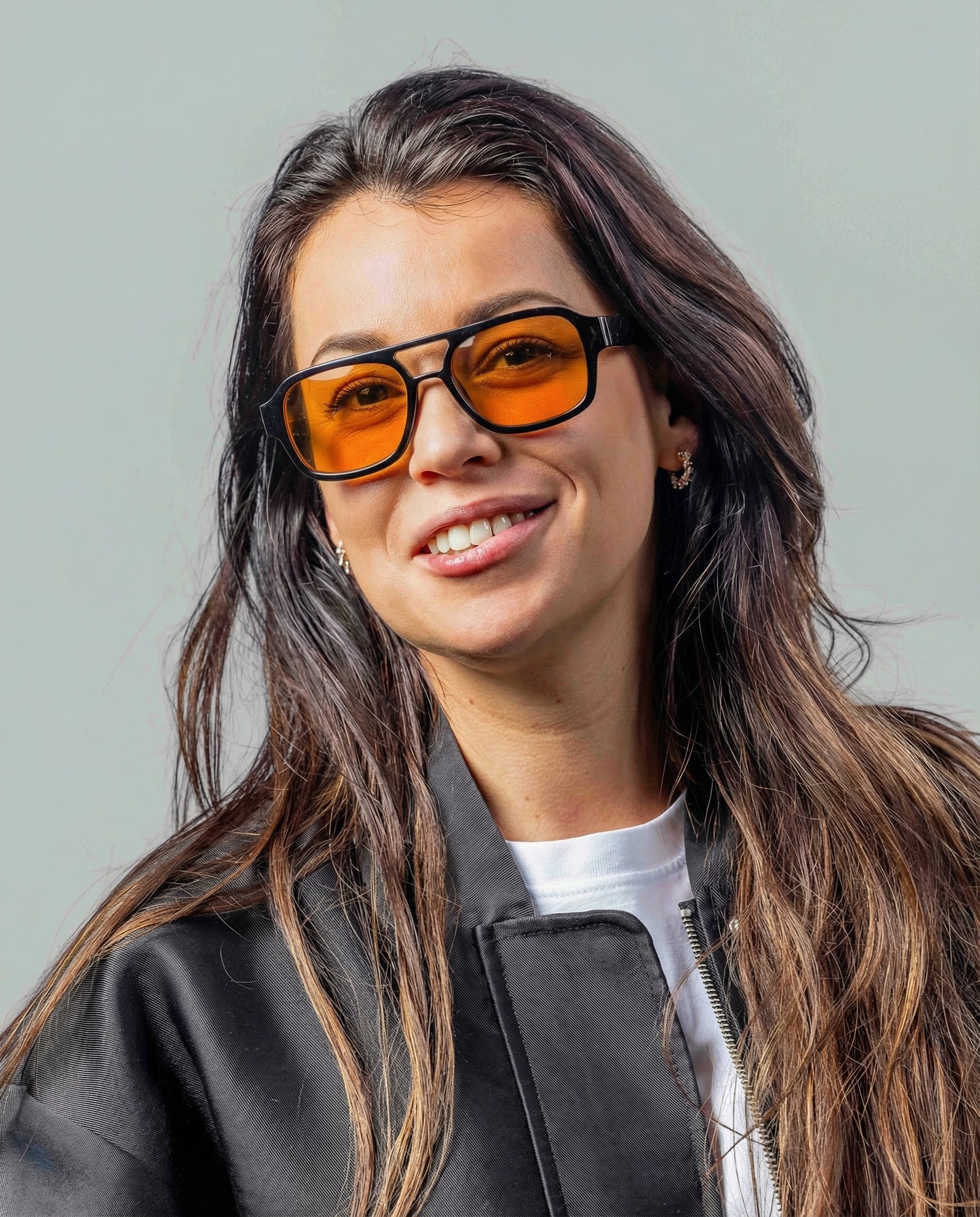 Vrouw met stijlvolle zonnebril met oranje glazen en zwarte montuur, perfect voor een modieuze look.