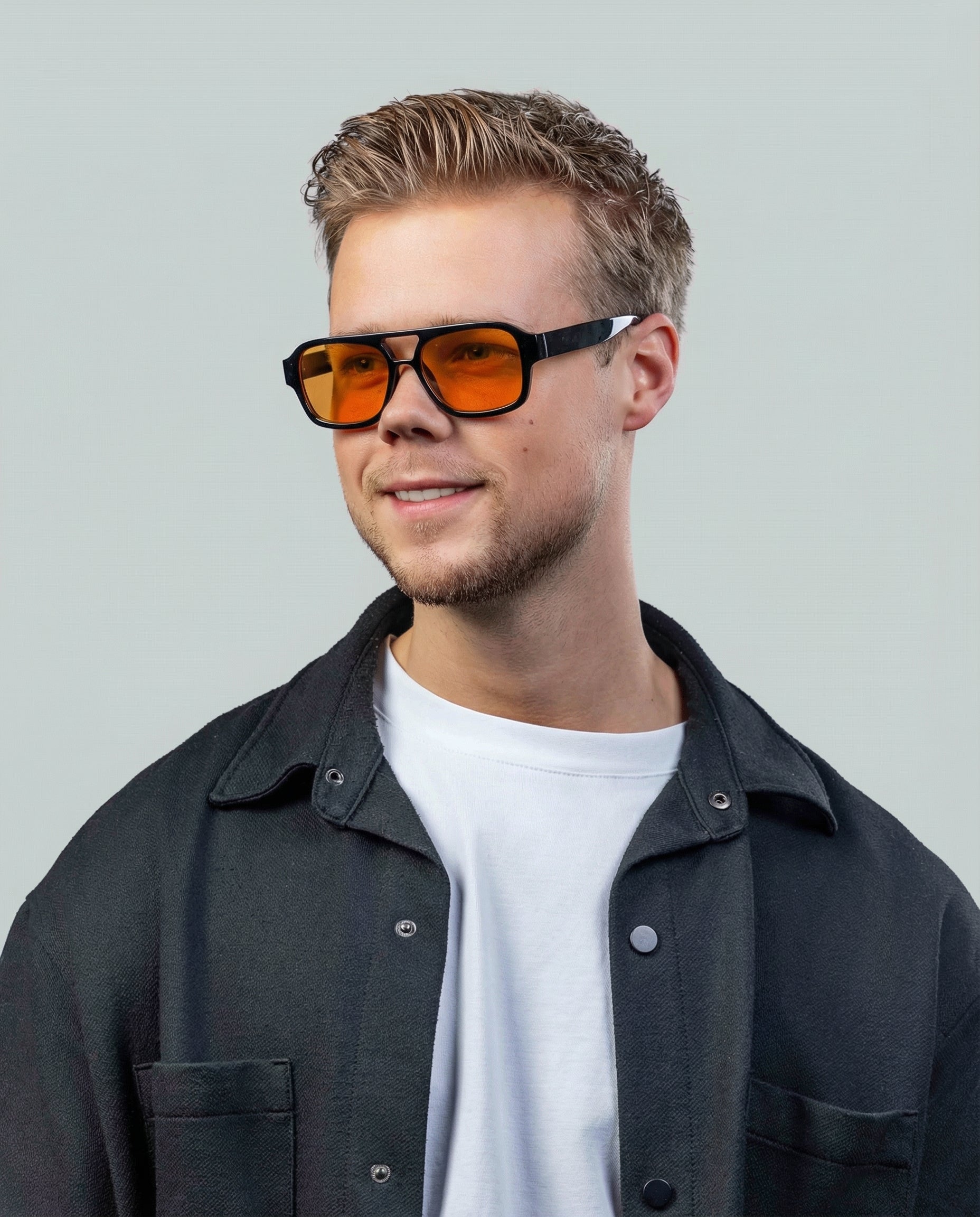 Man met stijlvolle zonnebril met oranje glazen en zwarte montuur, perfect voor een trendy look.