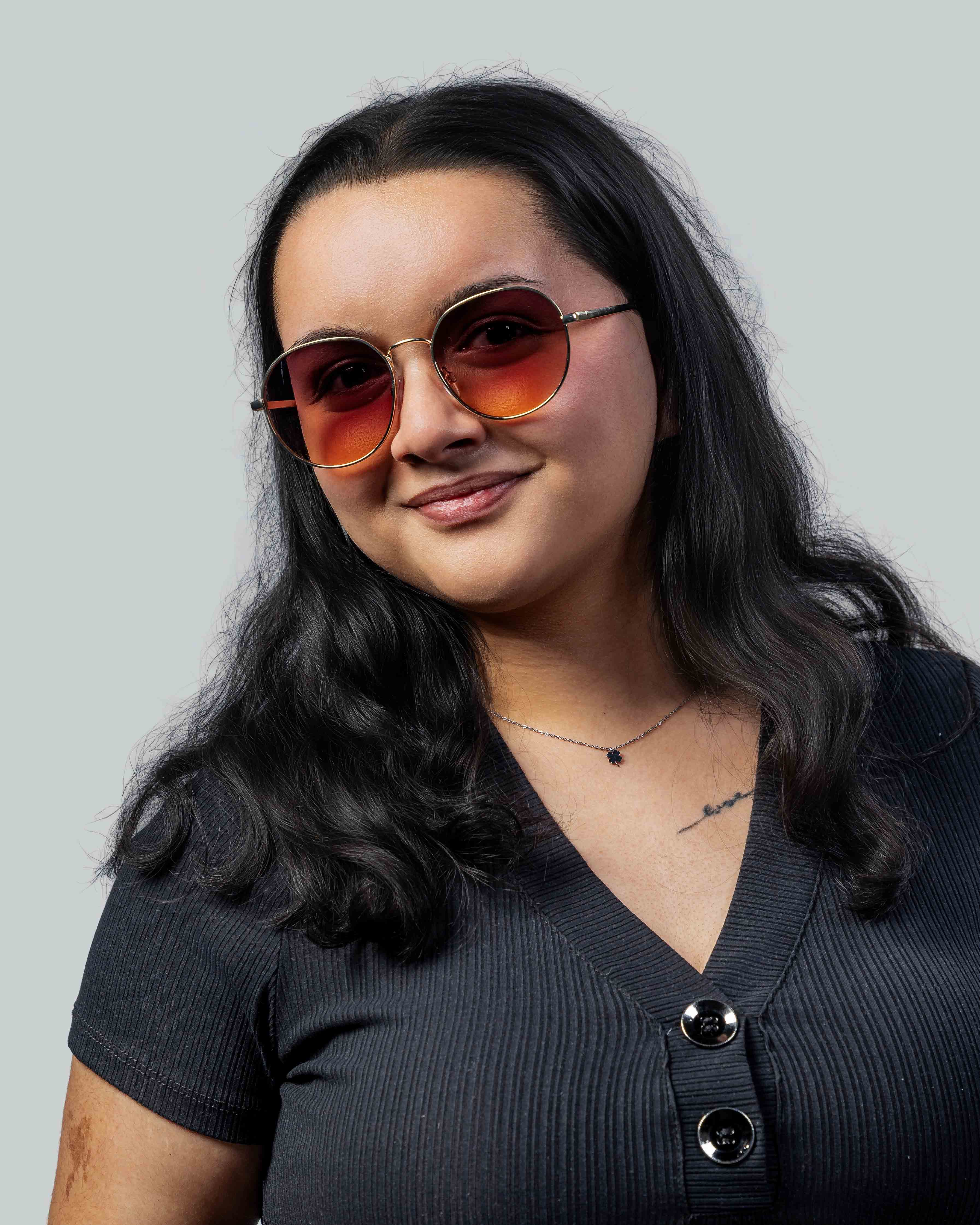 Vrouw met stijlvolle ronde zonnebril met gouden montuur en oranje glazen, perfect voor een modieuze look.
